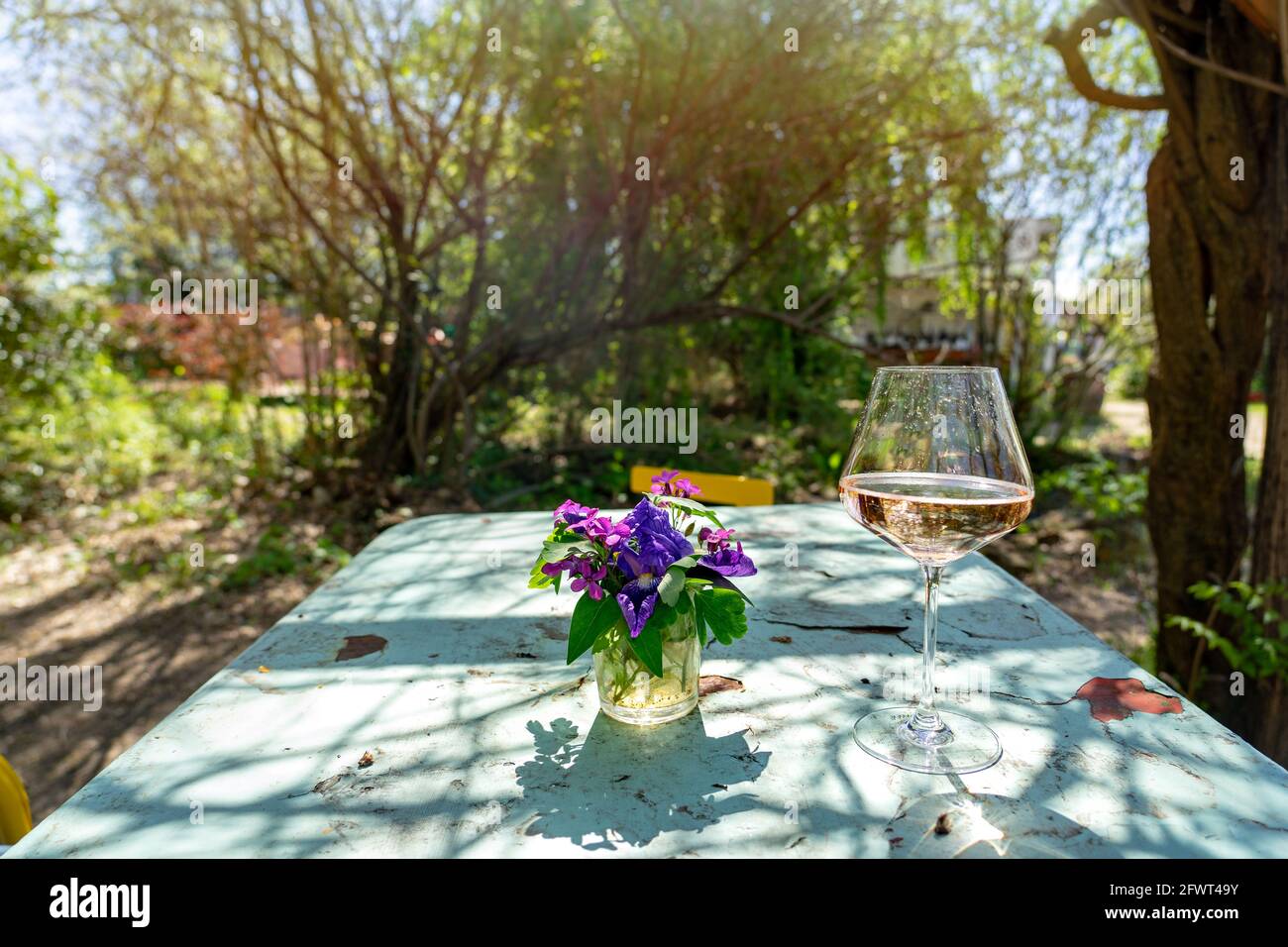 Vintage tavolo esterno in giardino con un bicchiere di vino rosato e fiori . Foto Stock