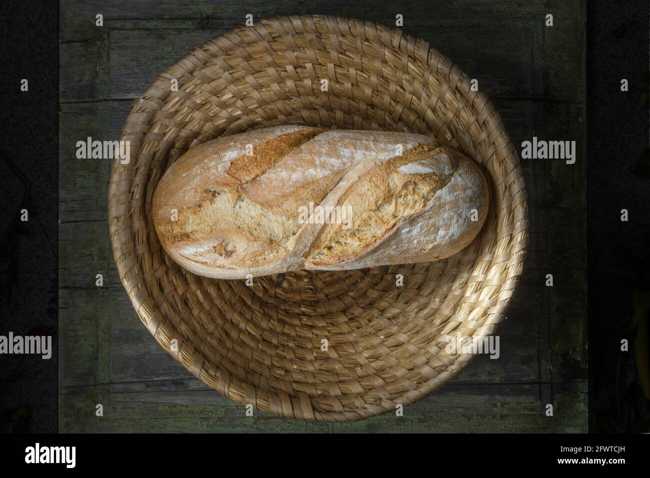 Macro Studio Foto di una pagnotta di pane su un tavolo di legno in un cesto di vimini. Ripresa dall'alto. Foto Stock