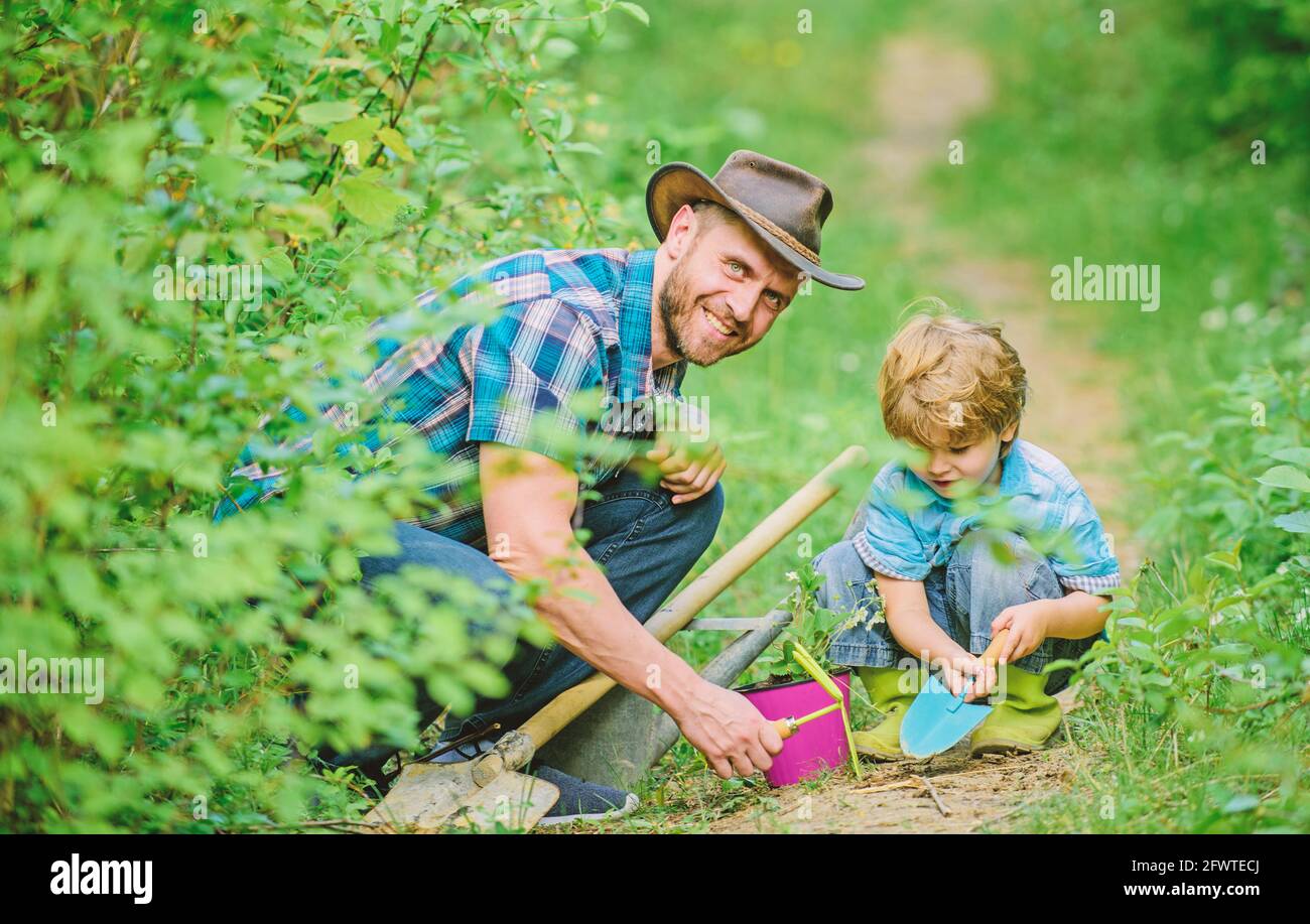 Ragazzino e padre in natura. Attrezzi di giardinaggio. Giardinaggio hobby. Papà insegnare le piante di cura del figlio piccolo. Routine di giardinaggio primaverile. Piantando Foto Stock