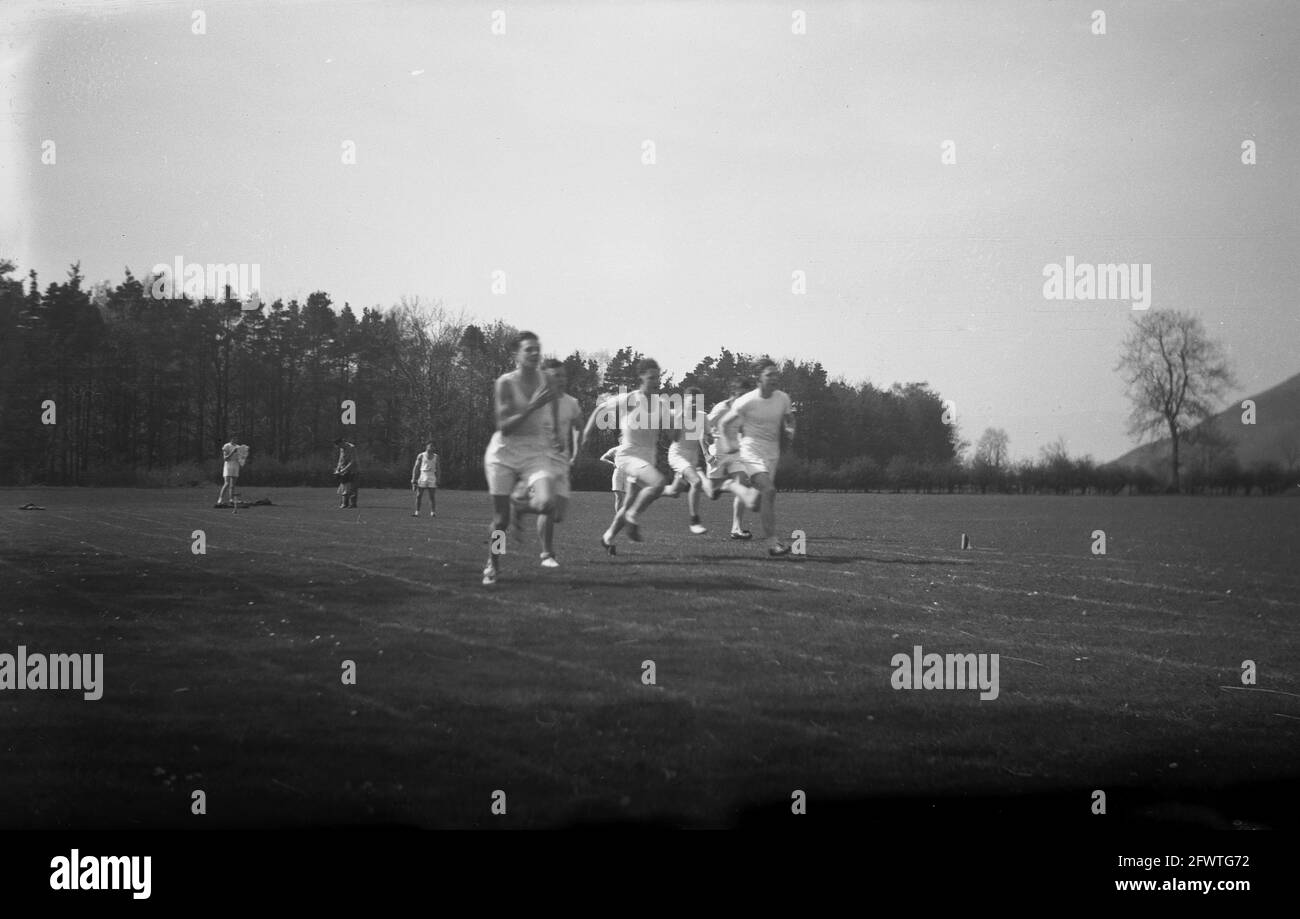1951, storico, fuori su una pista di corsa in erba in un grande campo sportivo, gli allievi superiori competono in una corsa di sprint, Highlands, Scozia. Foto Stock