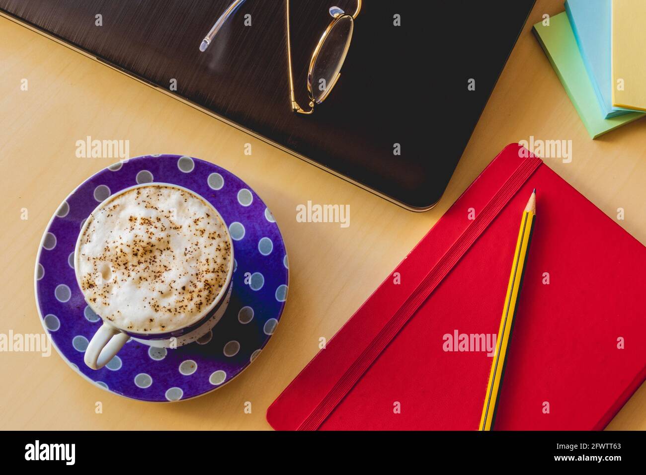 Tavolo con caffè, libro, matita, stickynote, computer portatile e bicchieri Foto Stock