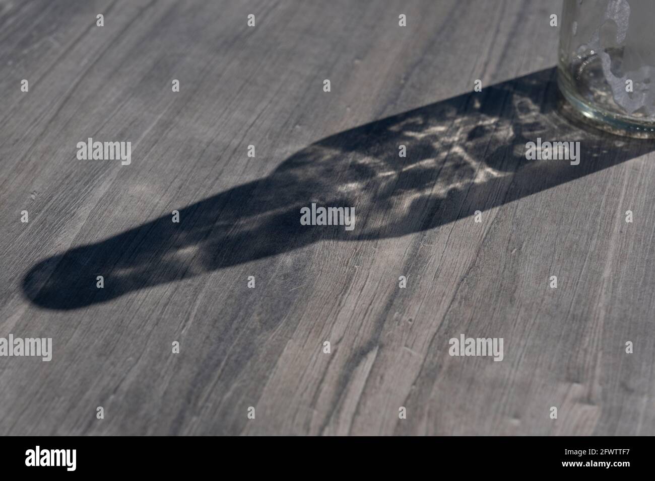 Helsinki / Finlandia - 22 MAGGIO 2021: Una vista astratta di una bottiglia di vetro che getta un'ombra su un tavolo di legno. Foto Stock