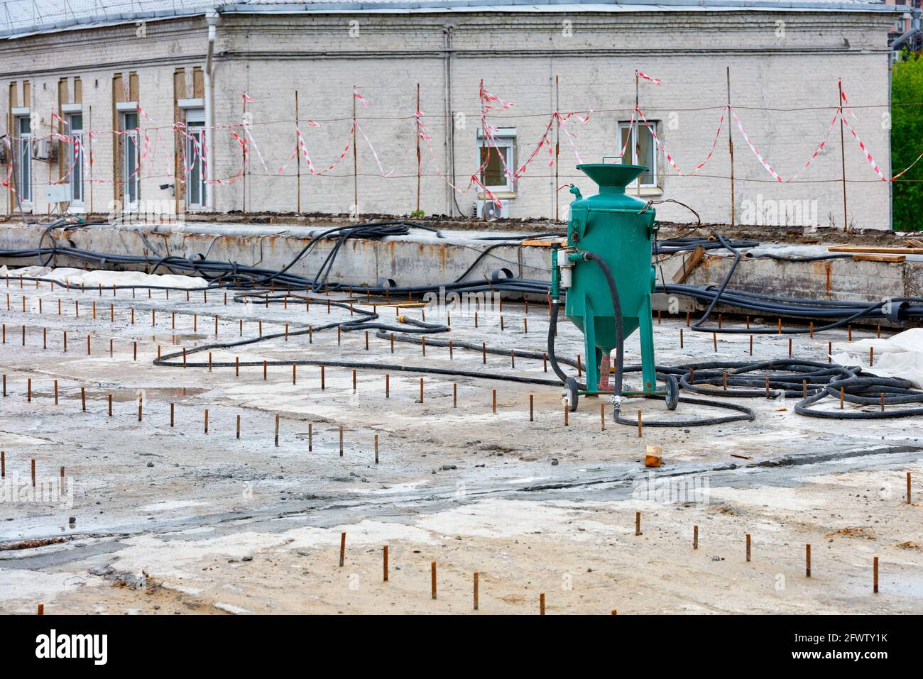 Una grande sabbiatrice verde si trova sullo sfondo di un'area di lavoro per pulire le parti metalliche arrugginite. Spazio di copia. Foto Stock