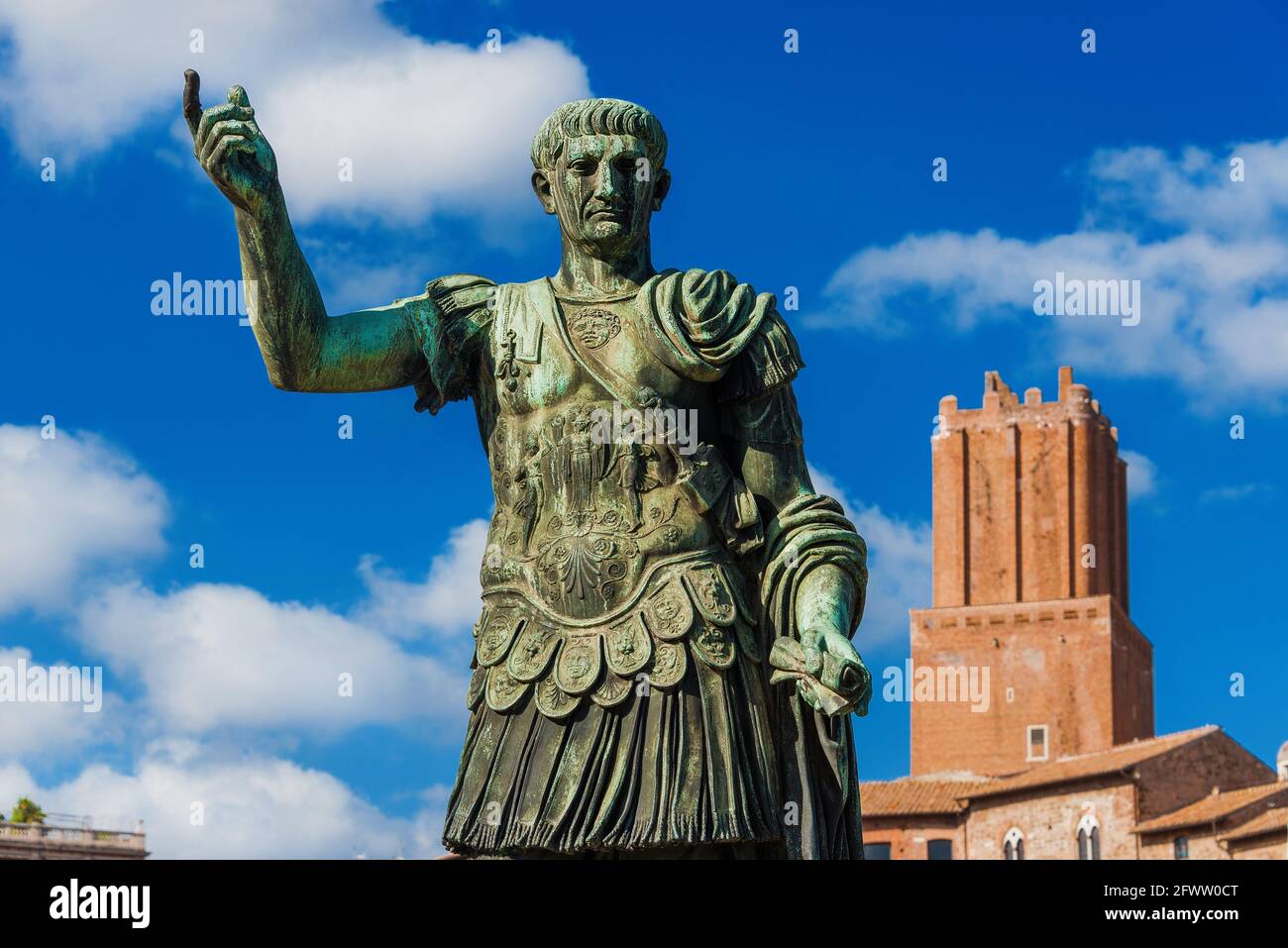 Imperatore Traiano di Roma antica statua con torre medievale Di Militia sullo sfondo lungo la Via dei fori Imperiali in Il centro storico di Roma Foto Stock