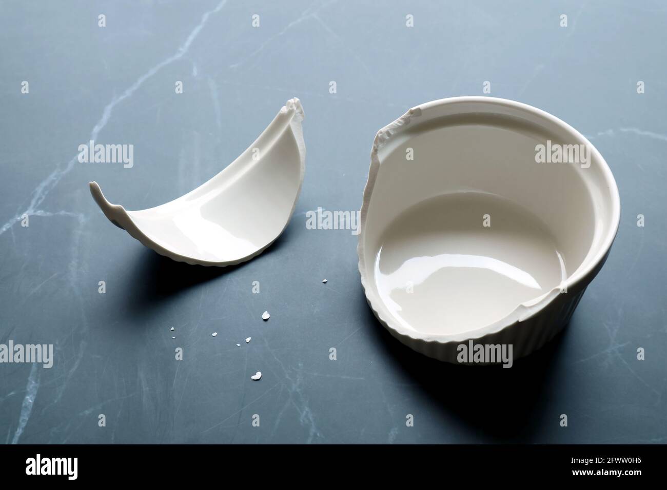 Teglia da forno in ceramica bianca rotta con frammenti su marmo nero piano cucina Foto Stock