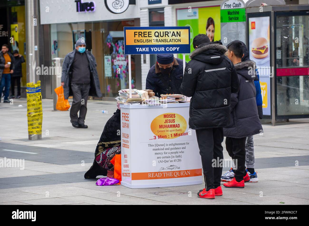 Slough, Berkshire, Regno Unito. 23 maggio 2021. Il Corano libero era dato fuori oggi in Slough High Street. Il tasso di infezione da rotolamento di sette giorni Covid-19 per 100,000 persone in Slough per la settimana che termina il 18 maggio è salito a 25.4, rispetto a 22.7. Dato che il numero di casi positivi di variante indiana di Covid-19 sta iniziando ad aumentare, la possibile eliminazione di tutte le restrizioni di blocco a giugno potrebbe ora essere in pericolo. Credito: Maureen McLean/Alamy Foto Stock