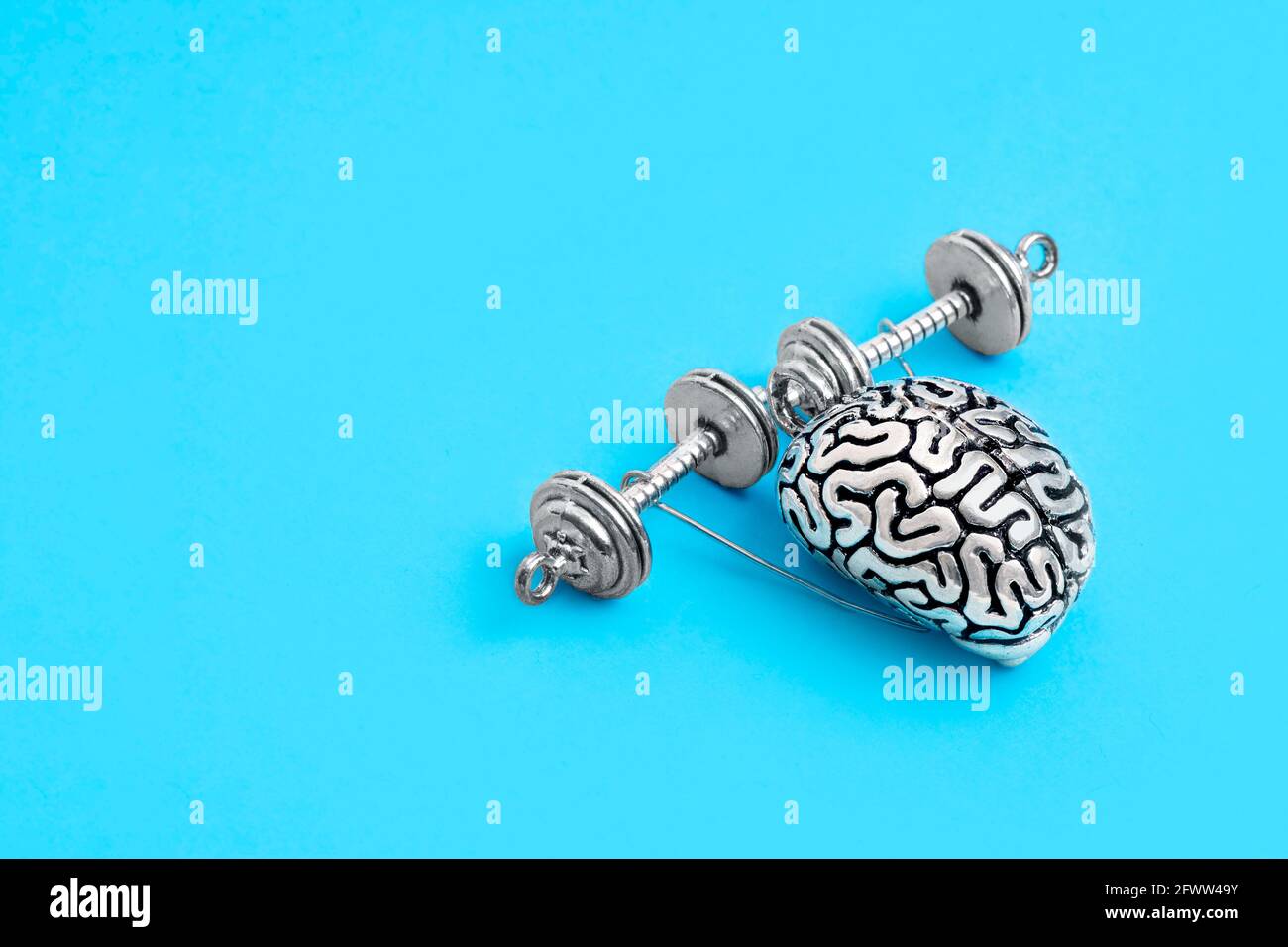 Copia in acciaio del cervello umano con mani che sollevano manubri isolati su blu. Il concetto di miglioramento della memoria attraverso l'esercizio. Foto Stock