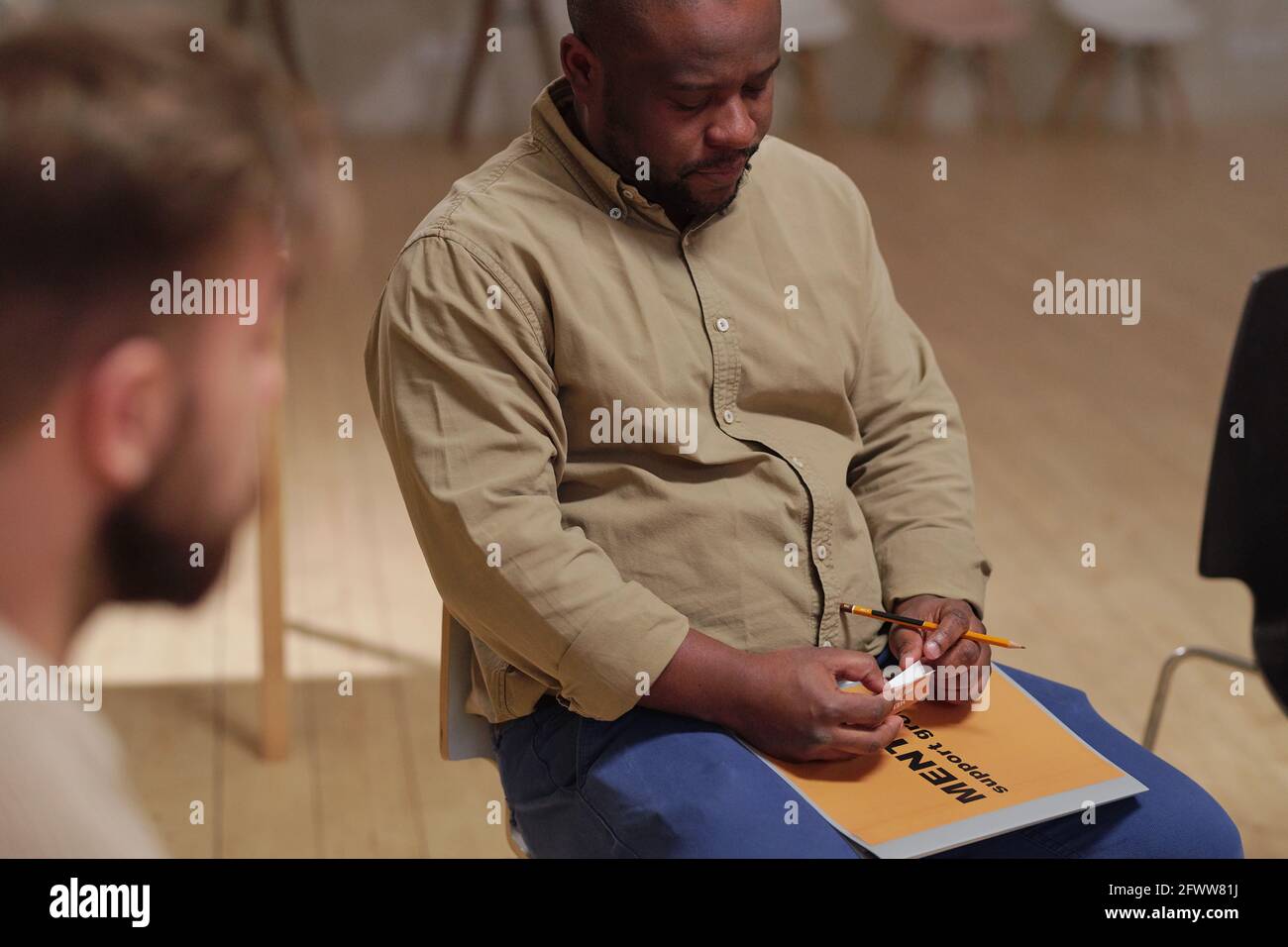 Giovane uomo tormentato di etnia africana seduto tra i pazienti di psicologo mentre descrive il suo problema Foto Stock