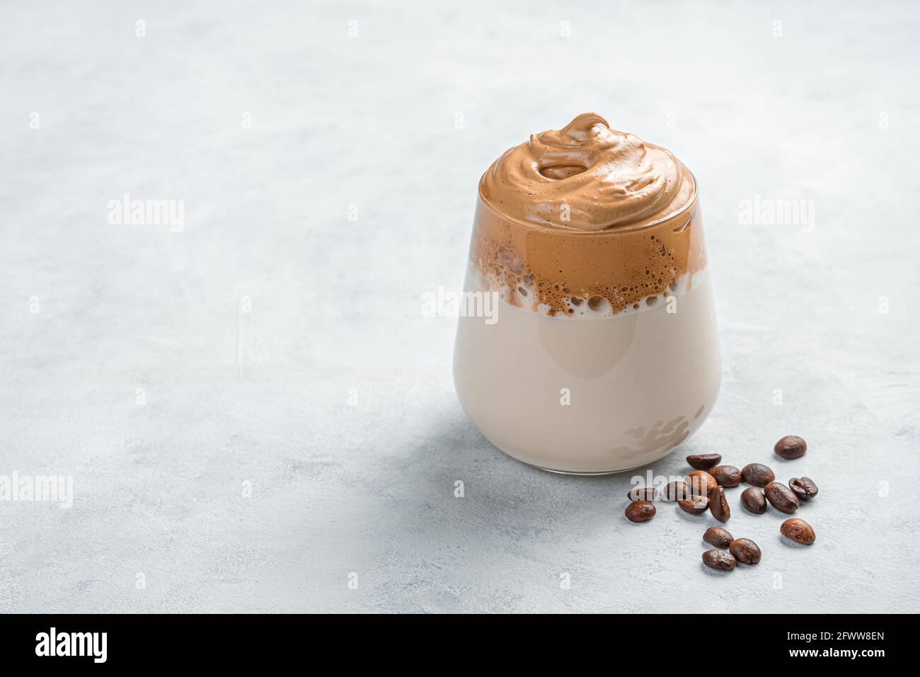 Caffè e chicchi di caffè Dalgona su sfondo grigio. Foto Stock
