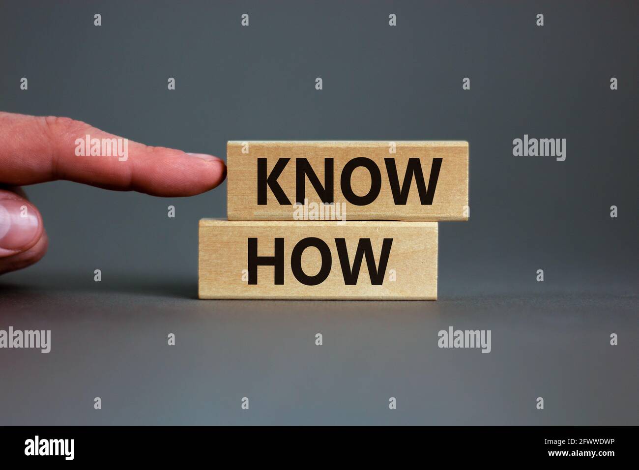 Conoscere il simbolo. Blocchi di legno con parole 'know how' su uno sfondo grigio bello, copia spazio. Mano uomo d'affari. Business, innovazione e know how con Foto Stock