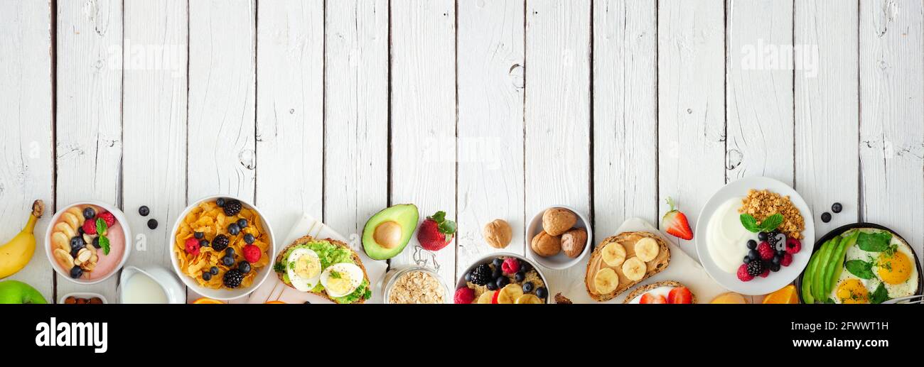Banner cibo sano per la colazione con bordo inferiore. Tavola con frutta, yogurt, ciotola per frullati, toast nutrienti, cereali e uova. Vista dall'alto o Foto Stock