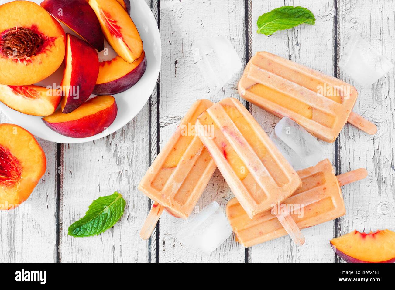 Pop-sicles di yogurt alla pesca estivo, scenario da tavolo con vista dall'alto su uno sfondo rustico di legno bianco Foto Stock