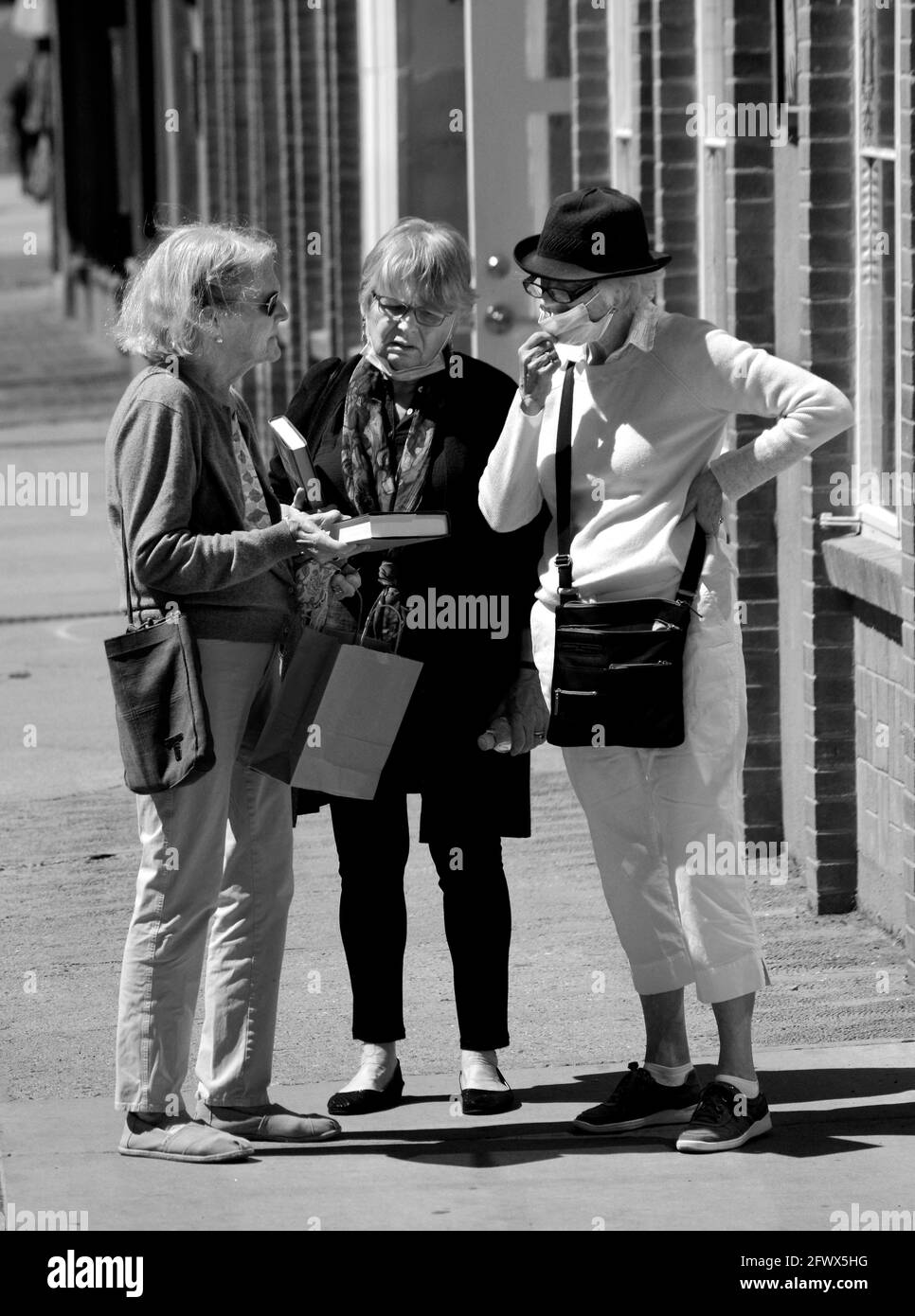 Tre donne senior si fermano a parlare fuori da una libreria a Santa Fe, New Mexico. Foto Stock