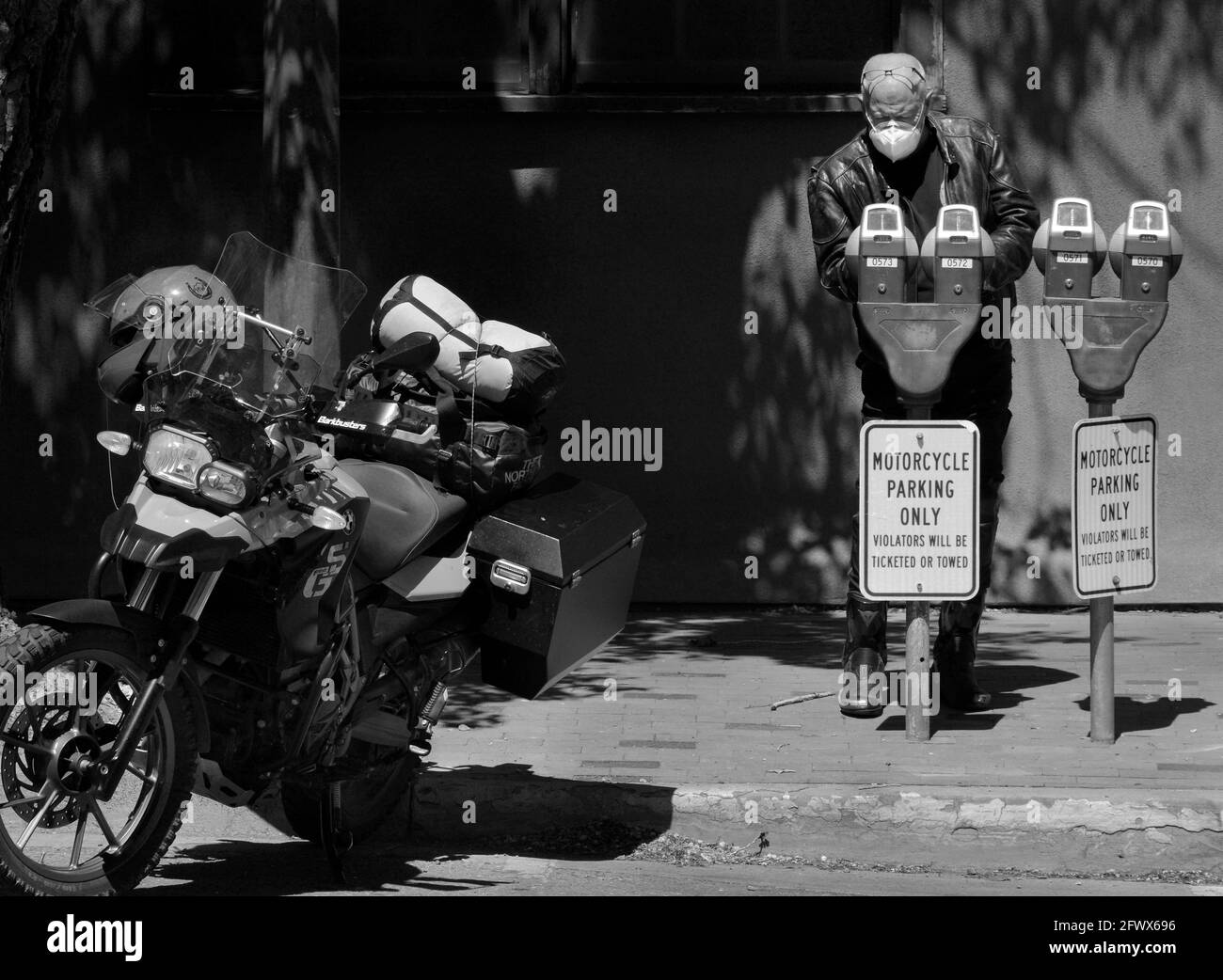 Un motociclista BMW che viaggia attraverso il sud-ovest americano mette le monete in un parchimetro a Santa Fe, New Mexico. Foto Stock