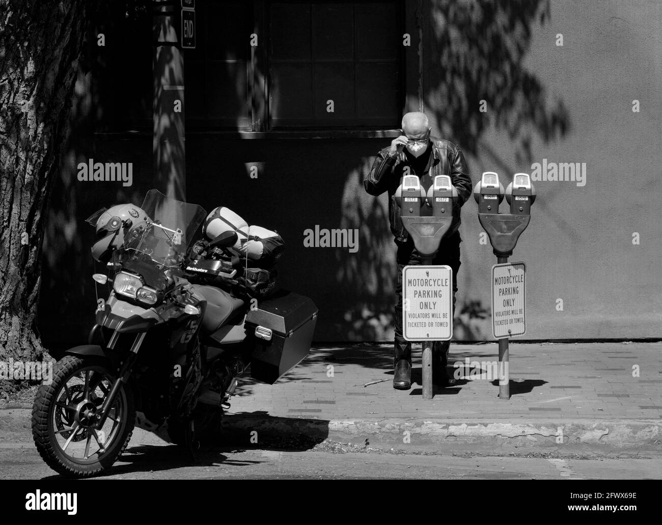 Un motociclista BMW che viaggia attraverso il sud-ovest americano mette le monete in un parchimetro a Santa Fe, New Mexico. Foto Stock