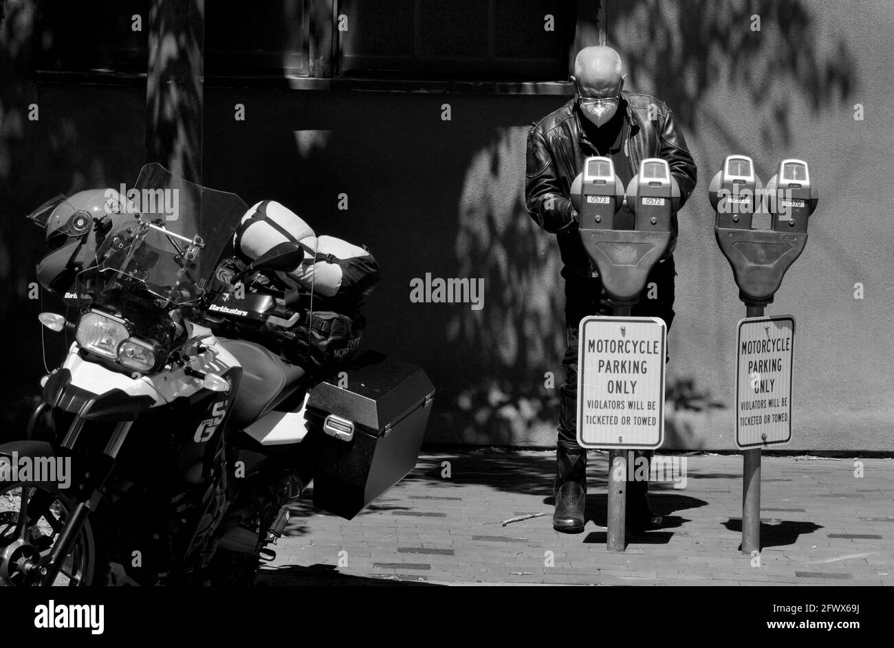 Un motociclista BMW che viaggia attraverso il sud-ovest americano mette le monete in un parchimetro a Santa Fe, New Mexico. Foto Stock