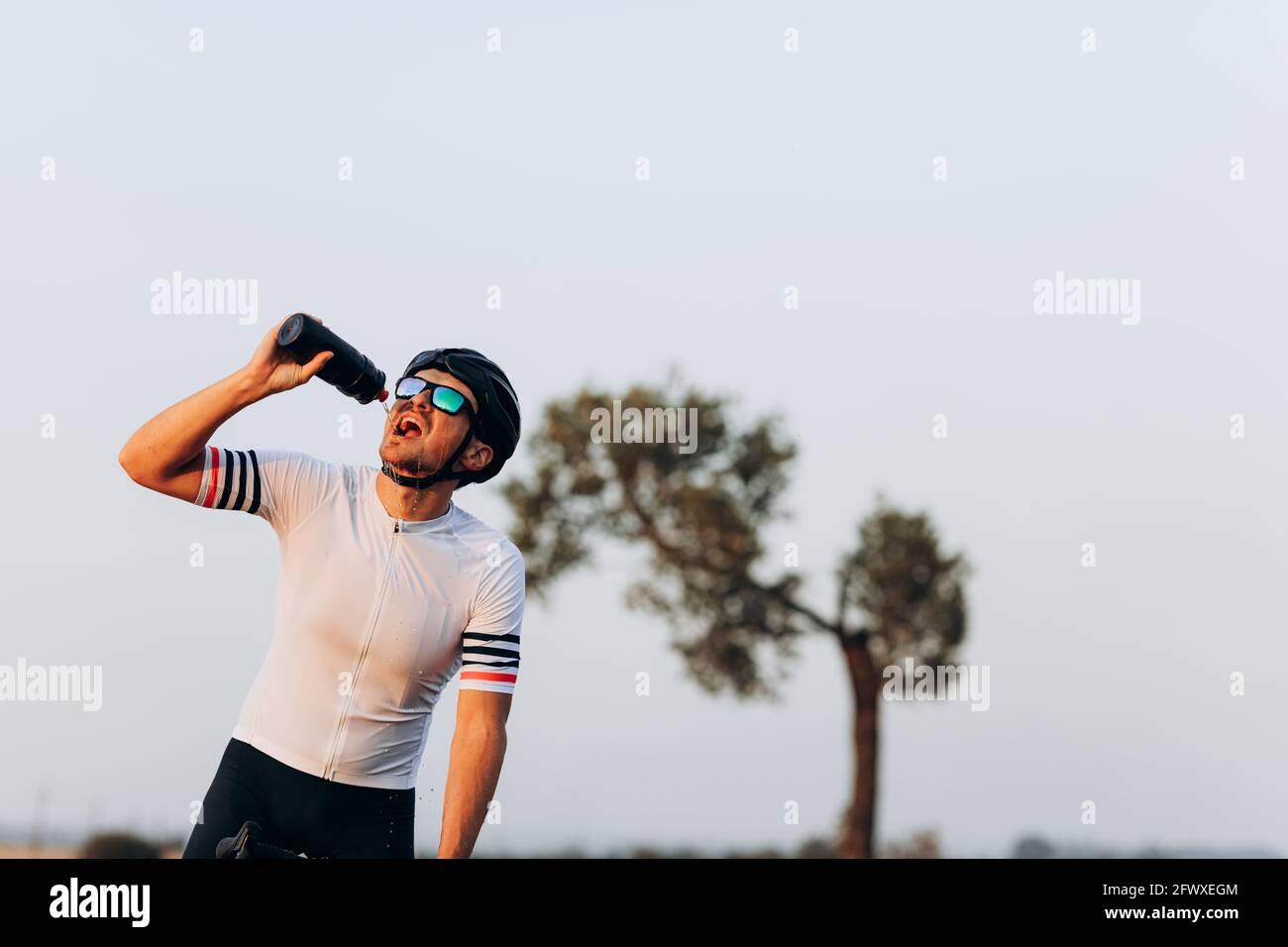 Ciclista esausta nell'acqua potabile del casco Foto Stock