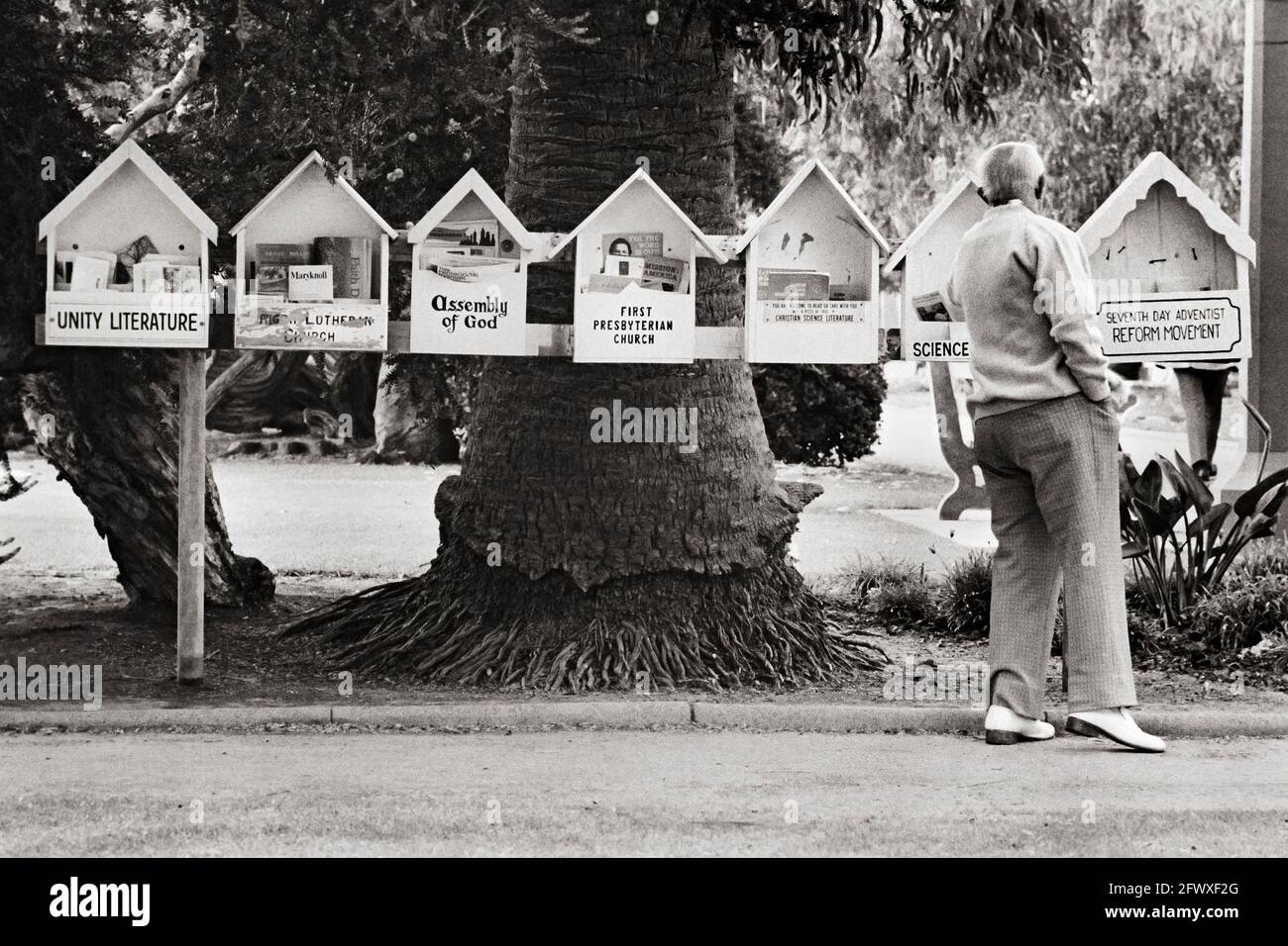 L'uomo anziano prova la letteratura religiosa da un buffet di scelta Foto Stock