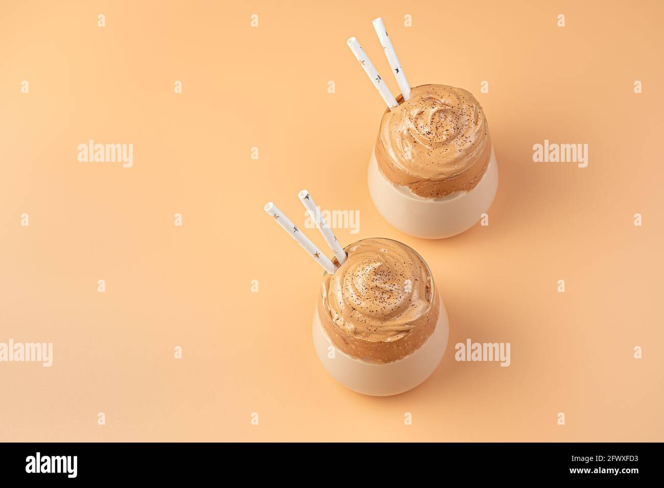Due bicchieri di dessert con schiuma montata su sfondo arancione. Foto Stock