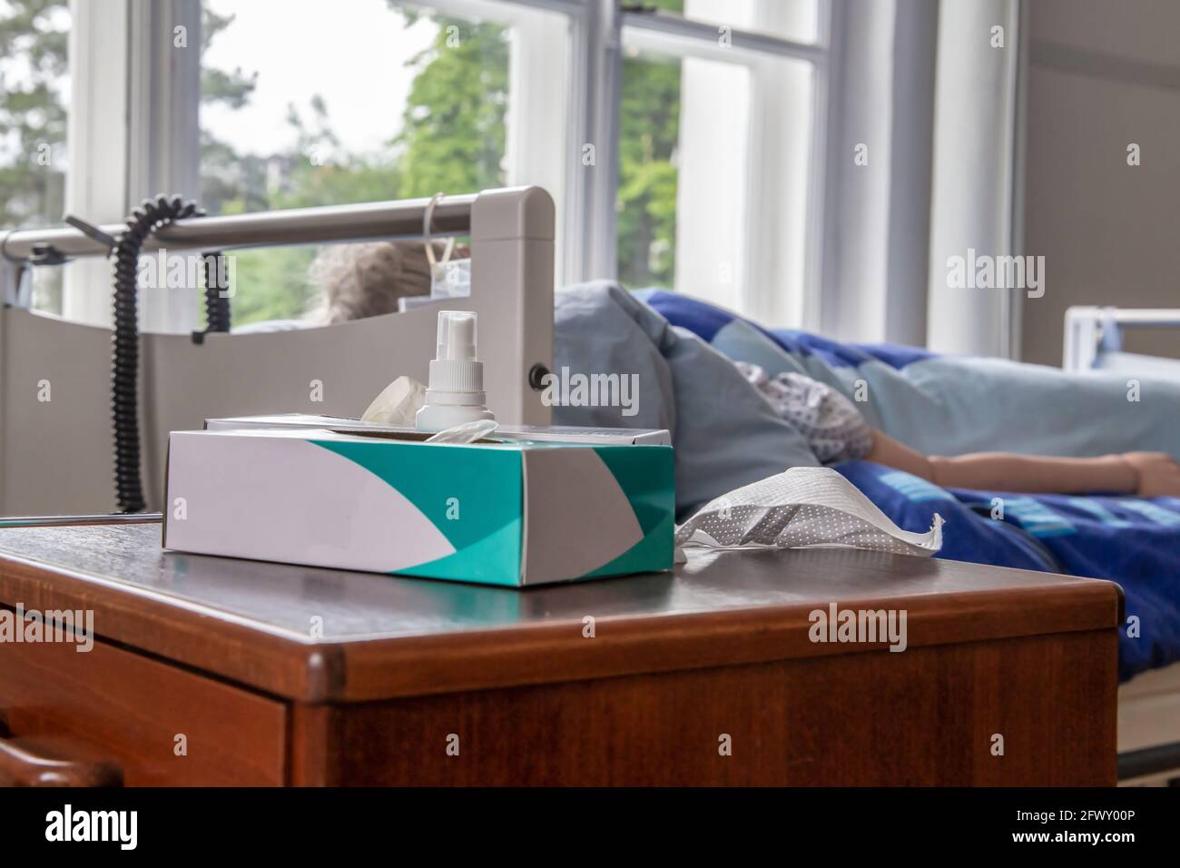 Scenario infermieristico: Guanti e una maschera di protezione del viso di fronte a un letto infermieristico Foto Stock