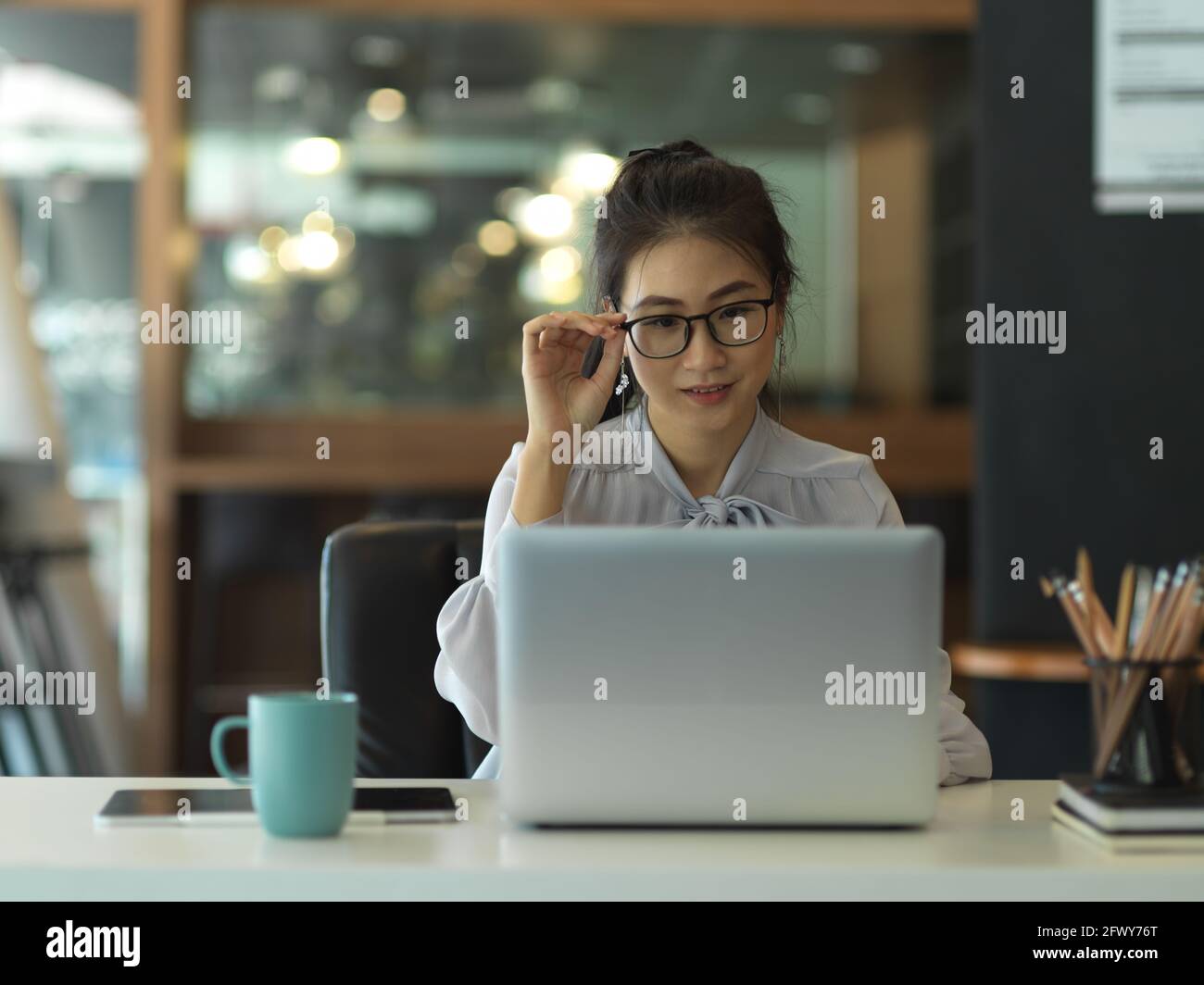 Ritratto di donna d'affari con occhiali concentrandosi sul suo lavoro con computer portatile in ufficio Foto Stock