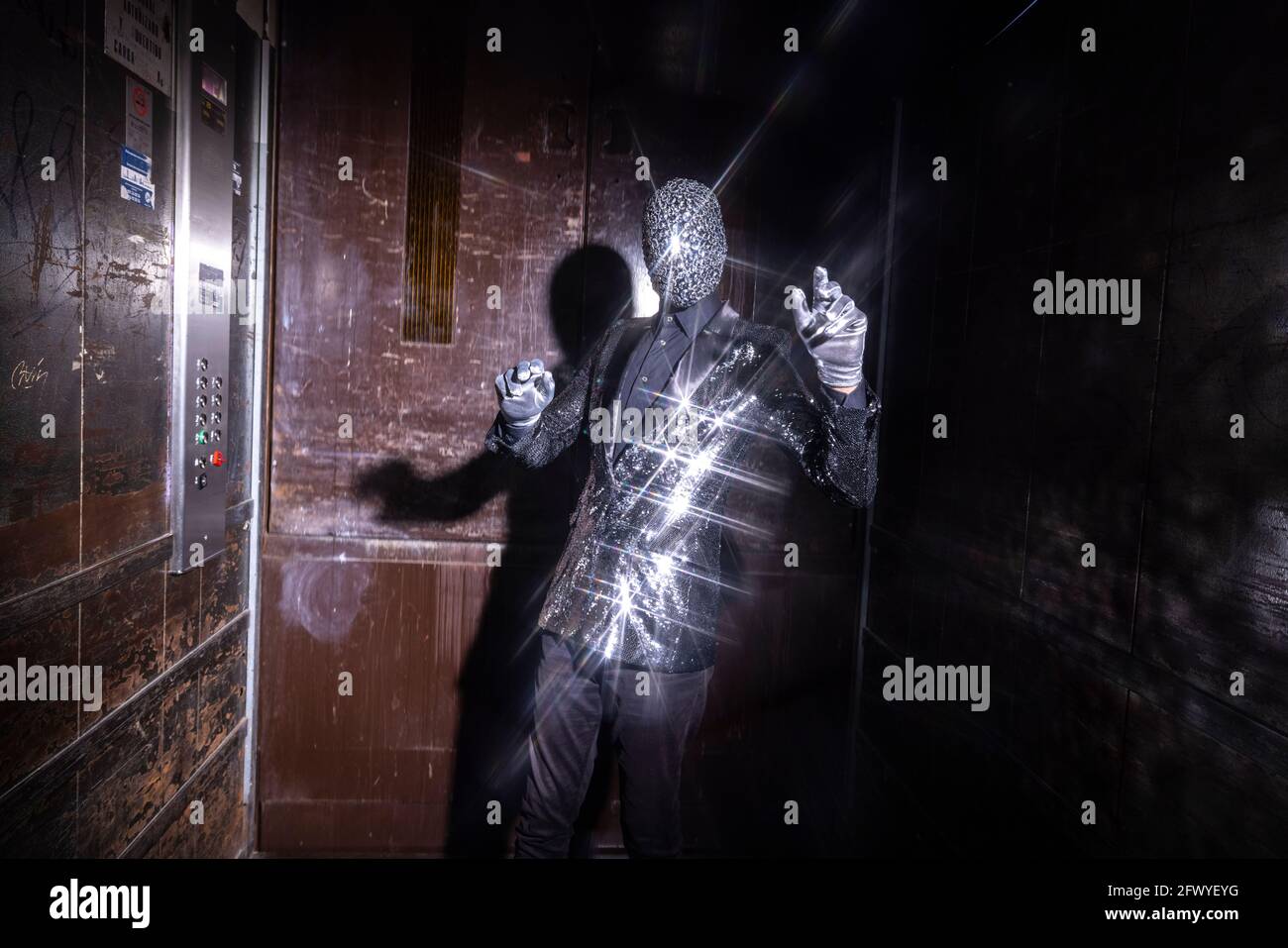 Uomo mascherato scintillante che balla in ascensore Foto Stock