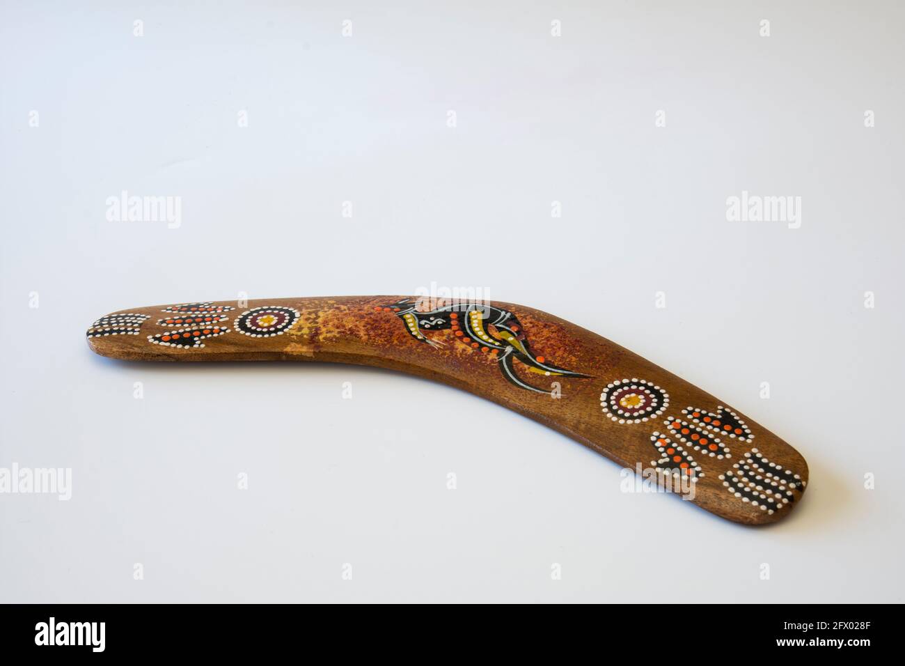 Boomerang colorato e ornato. Souvenir australiano, fuoco selettivo. Sfondo bianco isolato. Foto Stock