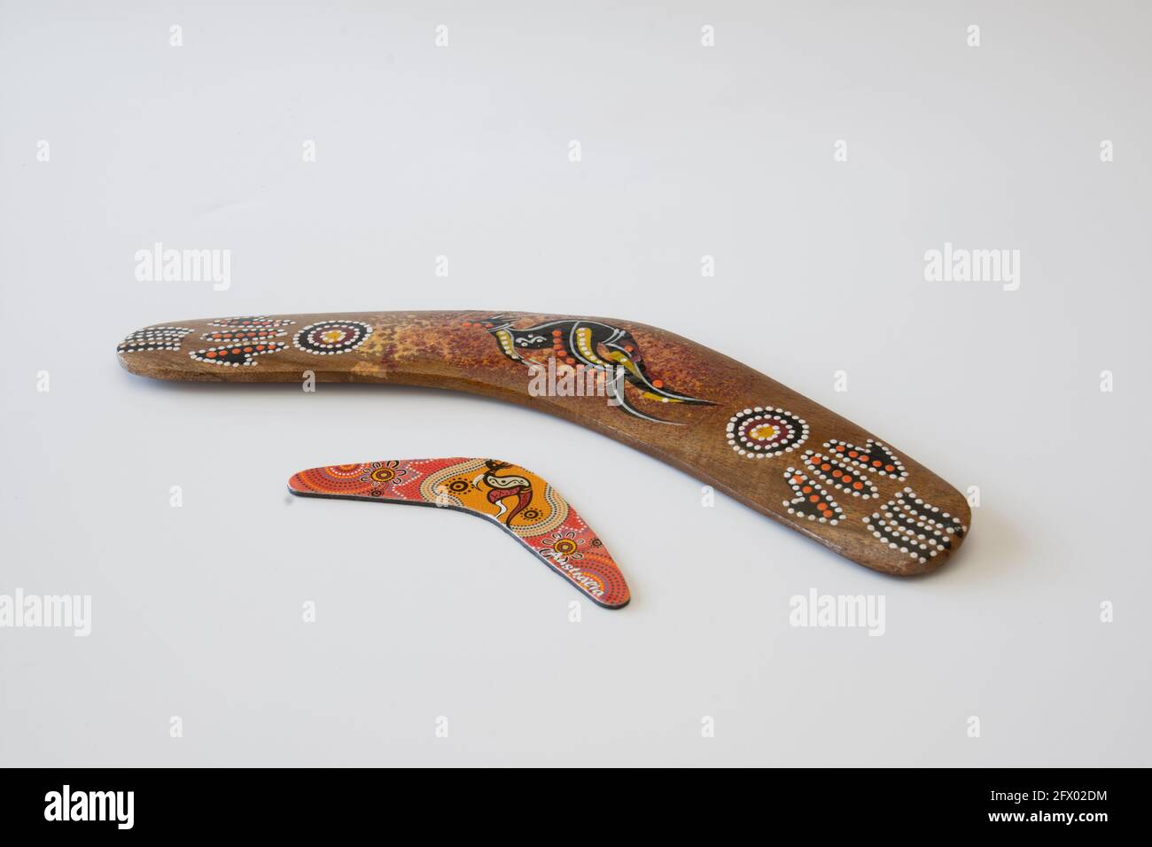 Uno di loro più grande. Boomerang colorati e ornati. Souvenir australiano, fuoco selettivo. Sfondo bianco isolato. Foto Stock