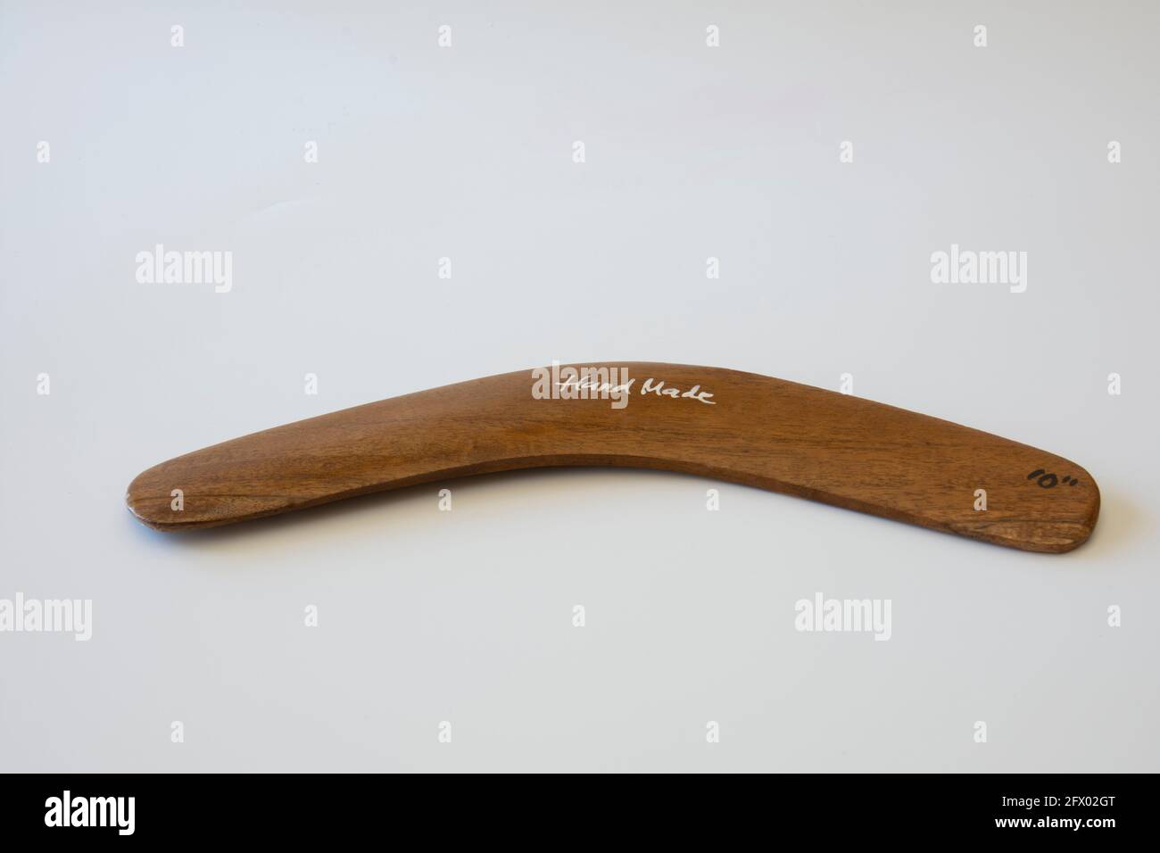 Boomerang colorato e ornato. Souvenir australiano, fuoco selettivo. Sfondo bianco isolato. Foto Stock