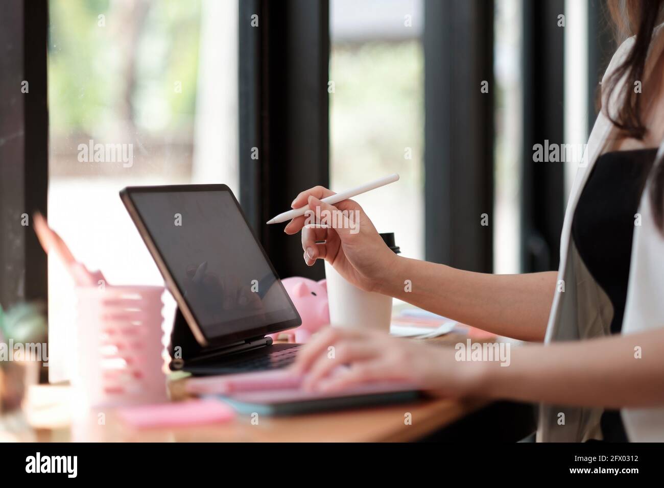 Primo piano mano di donna che lavora con un tablet digitale con penna stilo e tastiera intelligente. Foto Stock