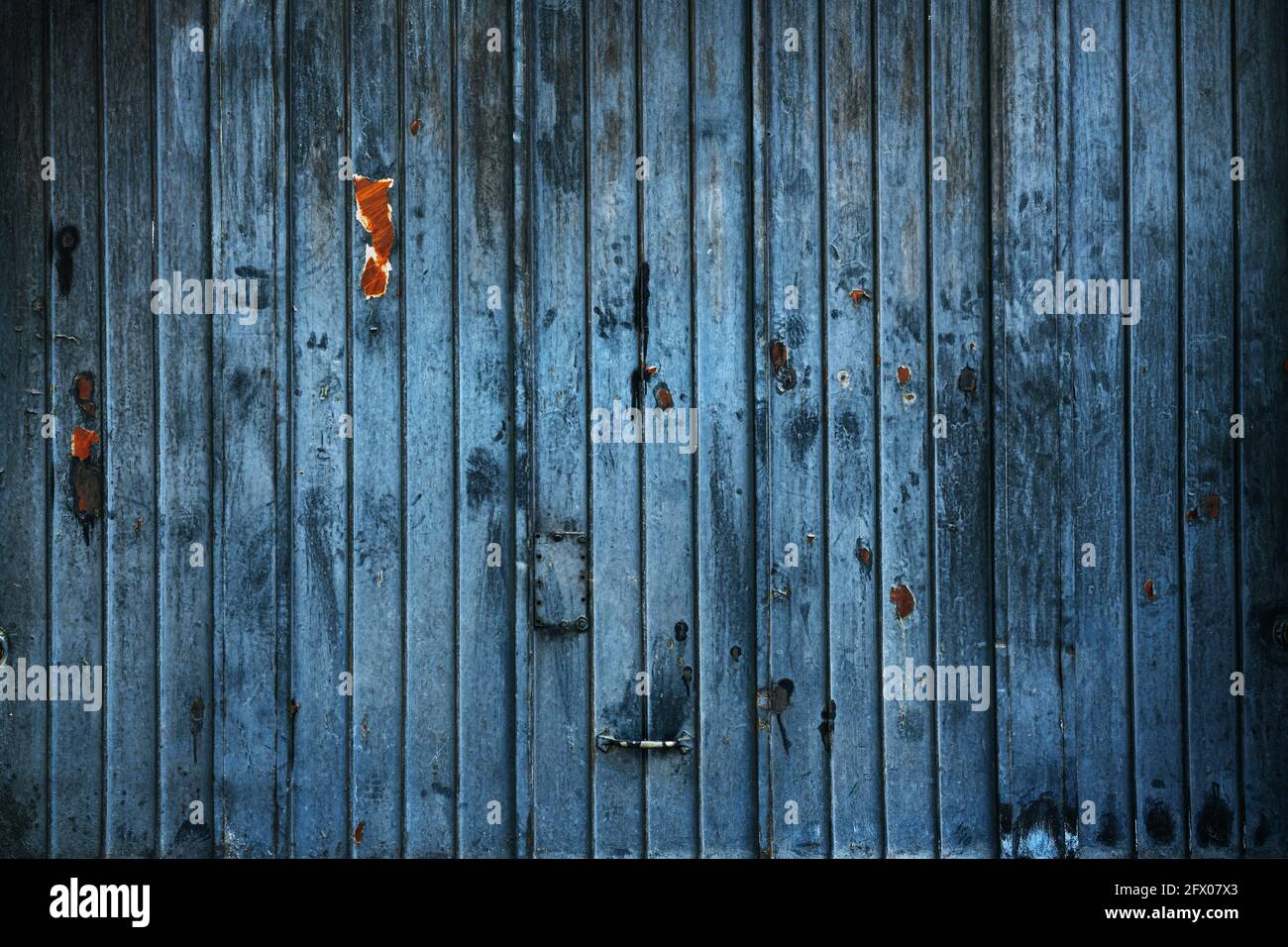 Porta da garage in metallo blu indossata con ruggine e segni di graffio per sfondo, vecchia grana Foto Stock