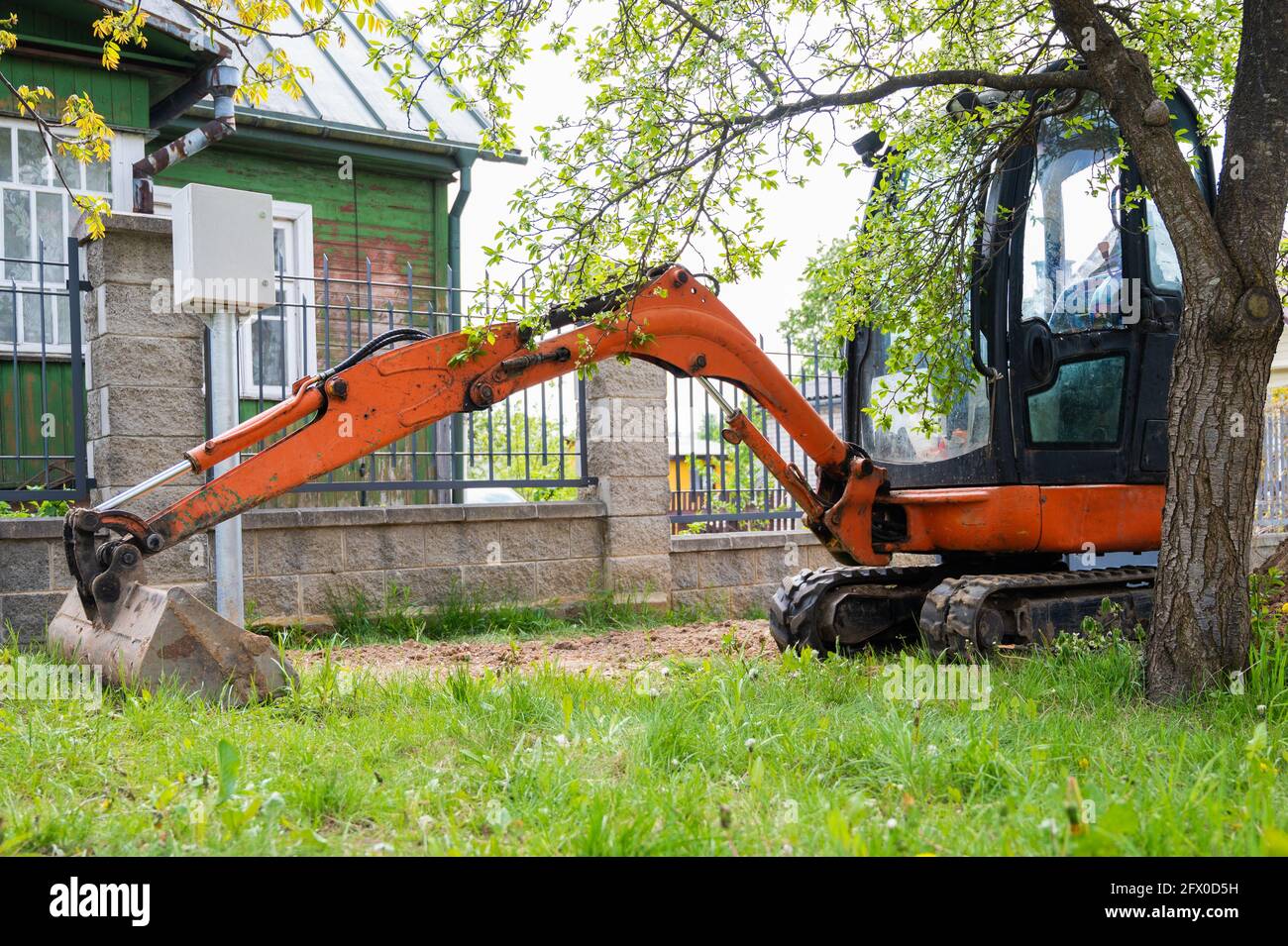 Mini escavatore in colore arancione. Noleggio attrezzature da costruzione. Foto Stock