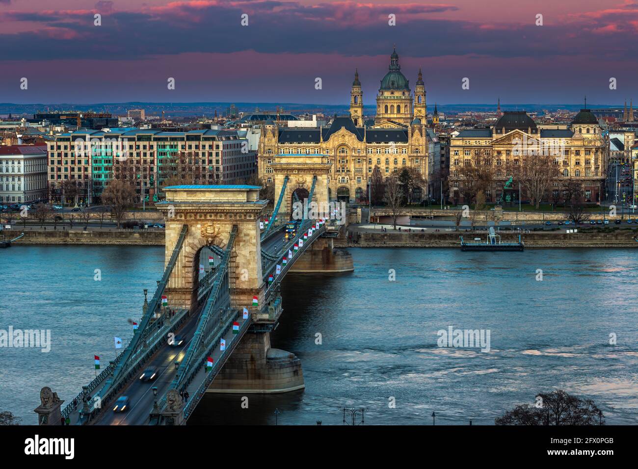 Budapest, Ungheria - il famoso Ponte delle catene di Szechenyi (Lanchid) al tramonto decorato con bandiere nazionali che celebrano il 15 marzo 1848 Civic revol Foto Stock