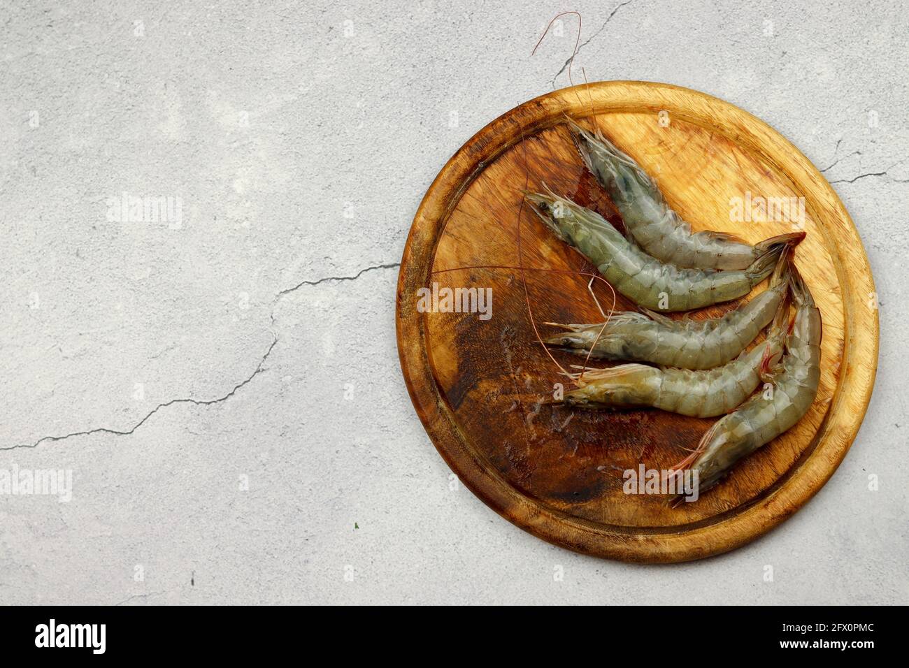 Gamberi crudi serviti su una tavola di legno su uno sfondo di legno chiaro. Vista dall'alto, disposizione piatta Foto Stock