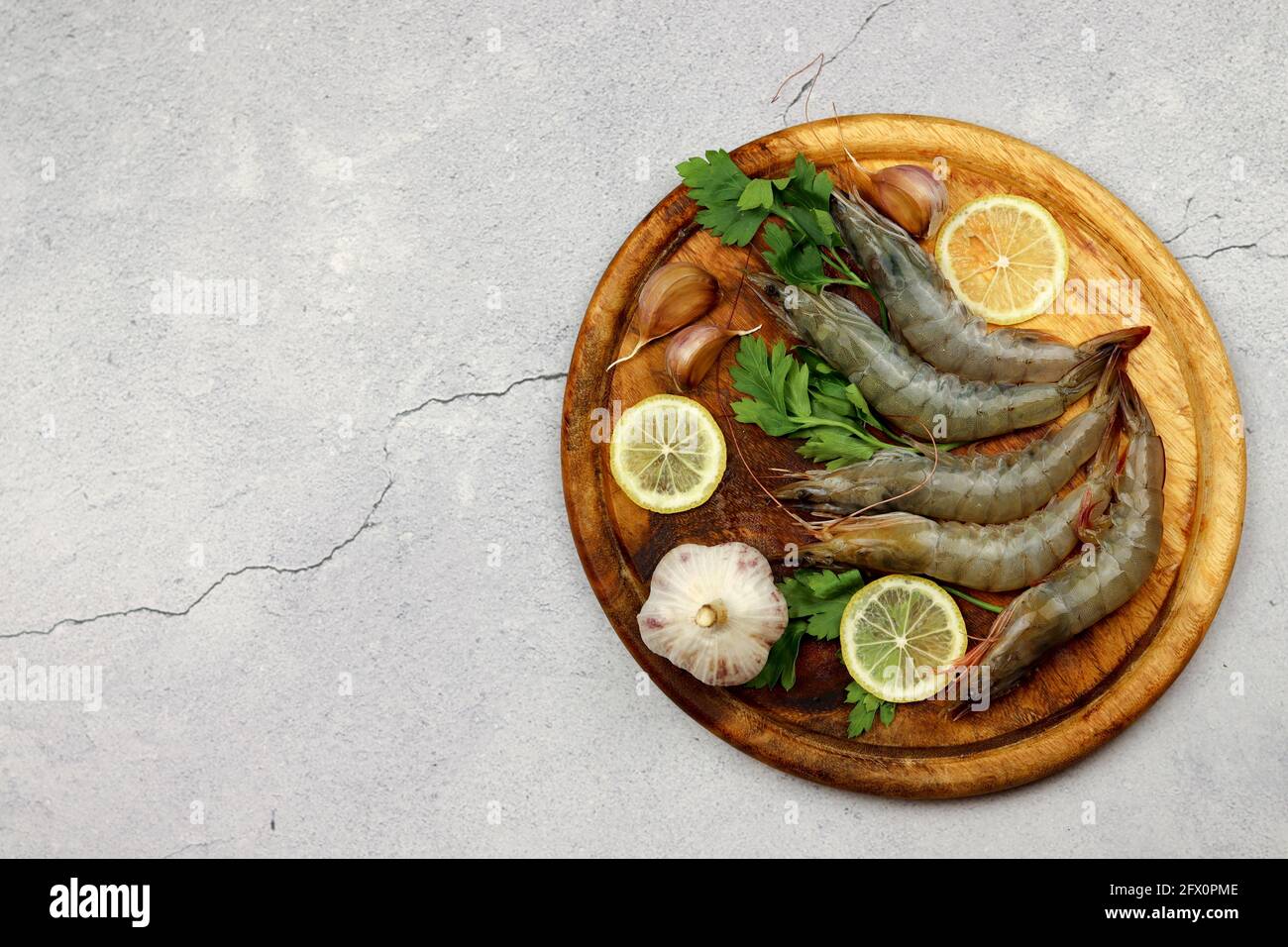 Gamberi crudi serviti su una tavola di legno su uno sfondo di legno chiaro. Vista dall'alto, disposizione piatta Foto Stock