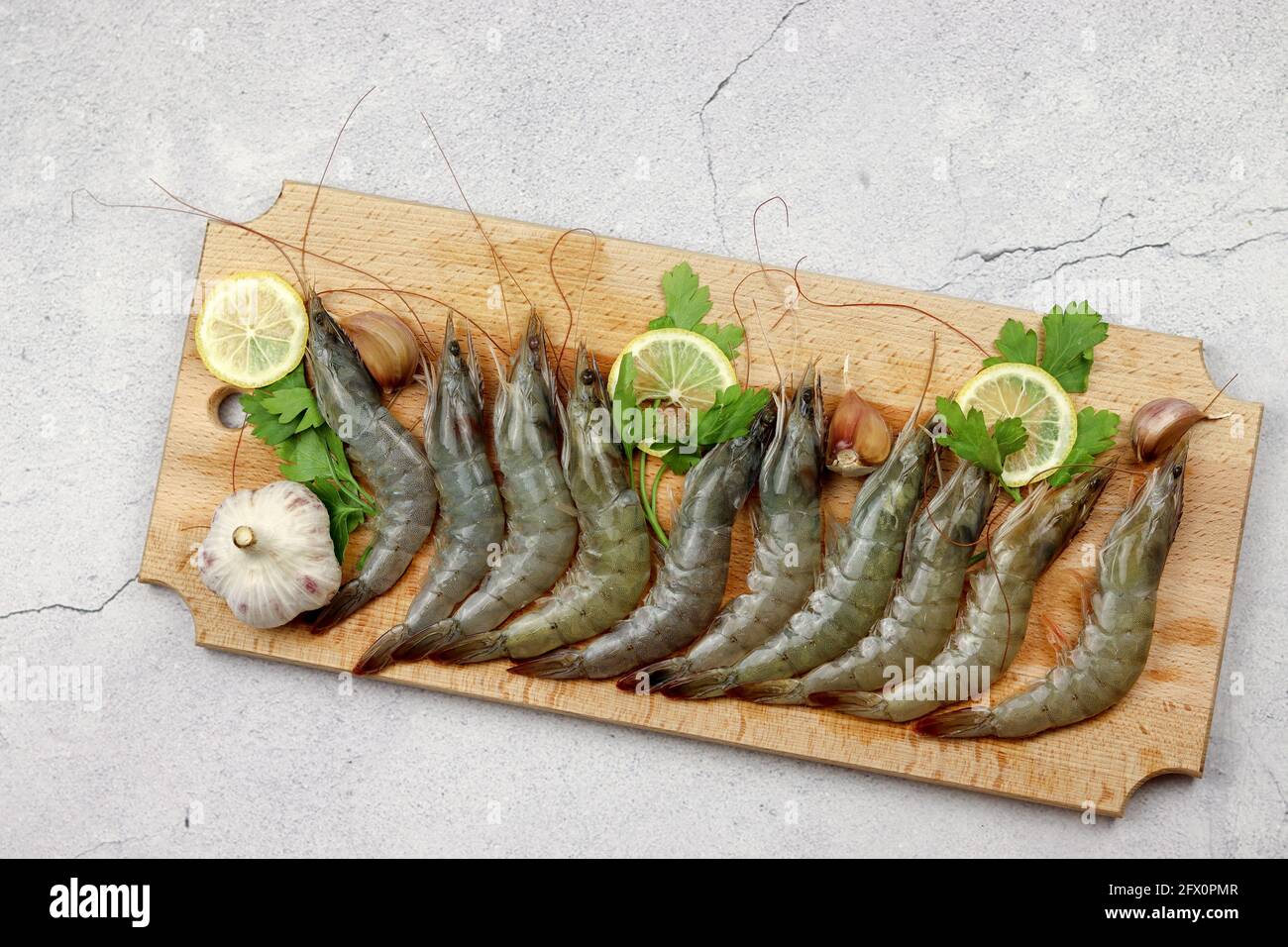 Gamberi crudi serviti su una tavola di legno su uno sfondo di legno chiaro. Vista dall'alto, disposizione piatta Foto Stock
