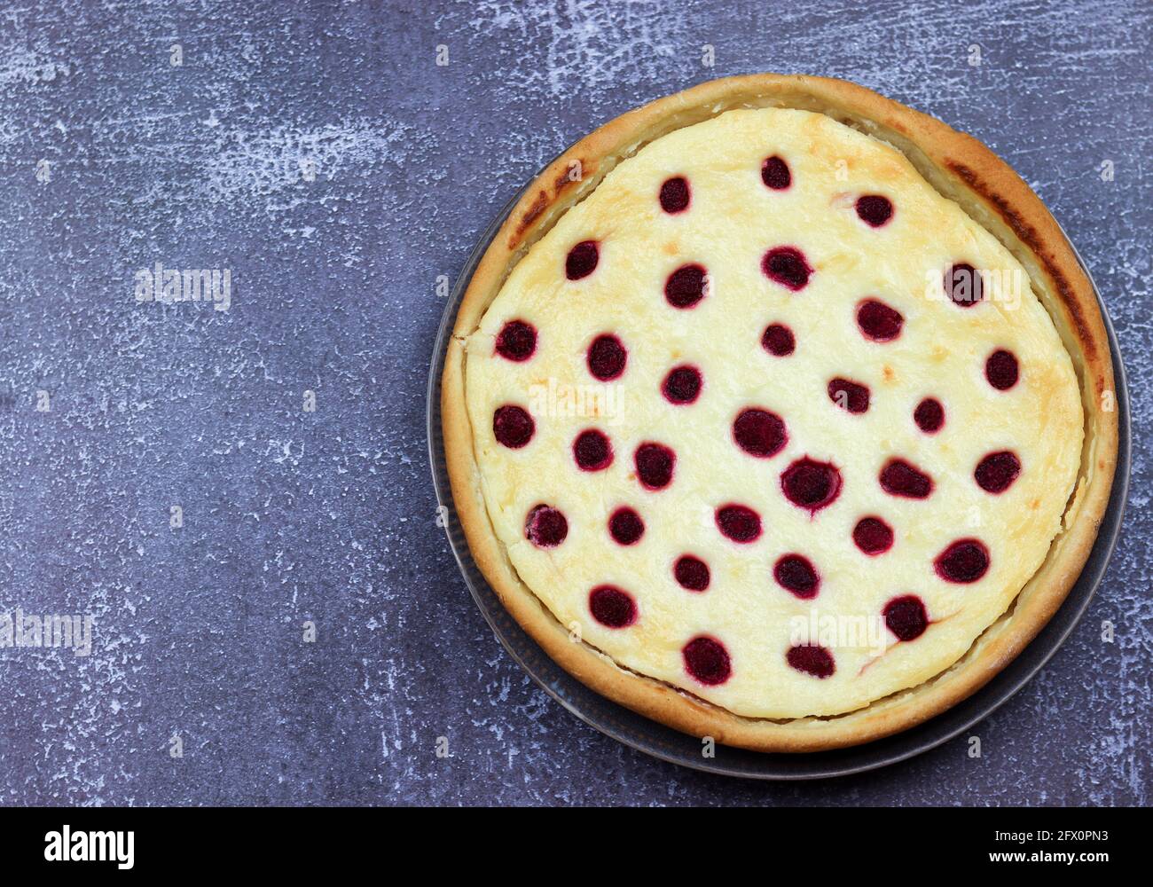 Torta dolce con formaggio di cottage e lamponi in un piatto su sfondo scuro. Vista dall'alto, disposizione piatta Foto Stock