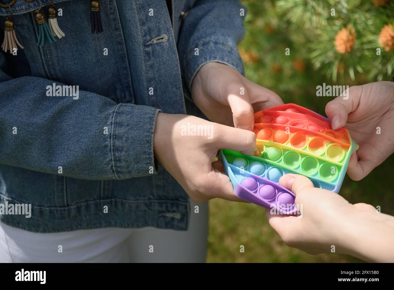 Ragazze che giocano in silicone popolare anti-stress Pop it in forma esagonale giocattolo. Primo piano. All'aperto. Concavità semplice. Foto Stock