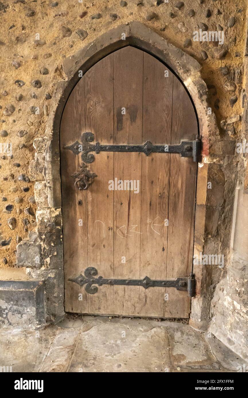 Una vecchia porta in rovere ad arco con lunghe cerniere nere e. una serratura in muratura medievale Foto Stock