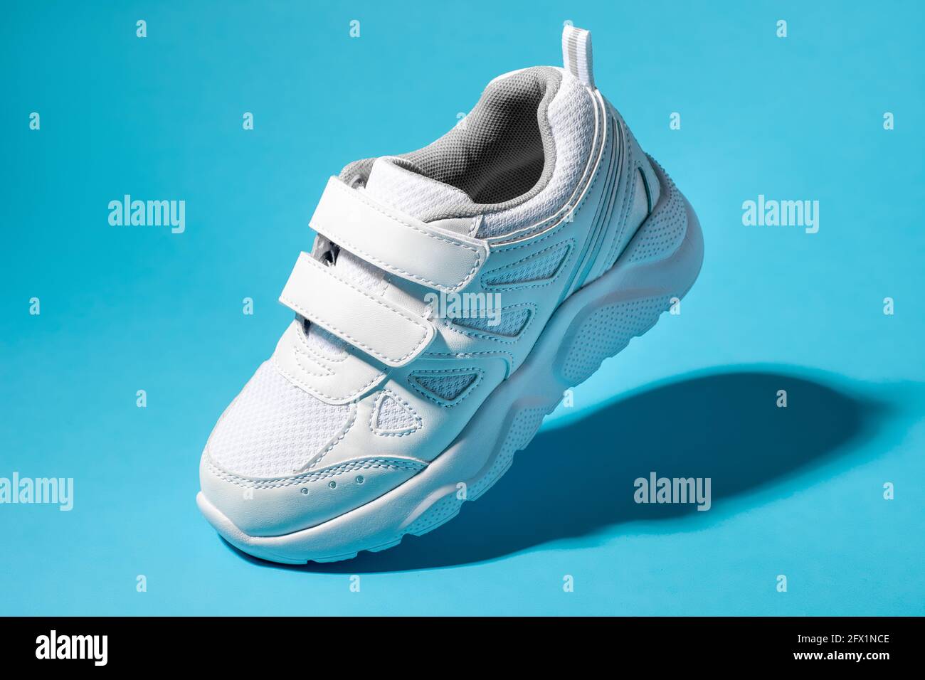 scarpe da ginnastica per bambini macro flying bianche con chiusure in velcro  isolate uno sfondo blu con luce intensa Foto stock - Alamy
