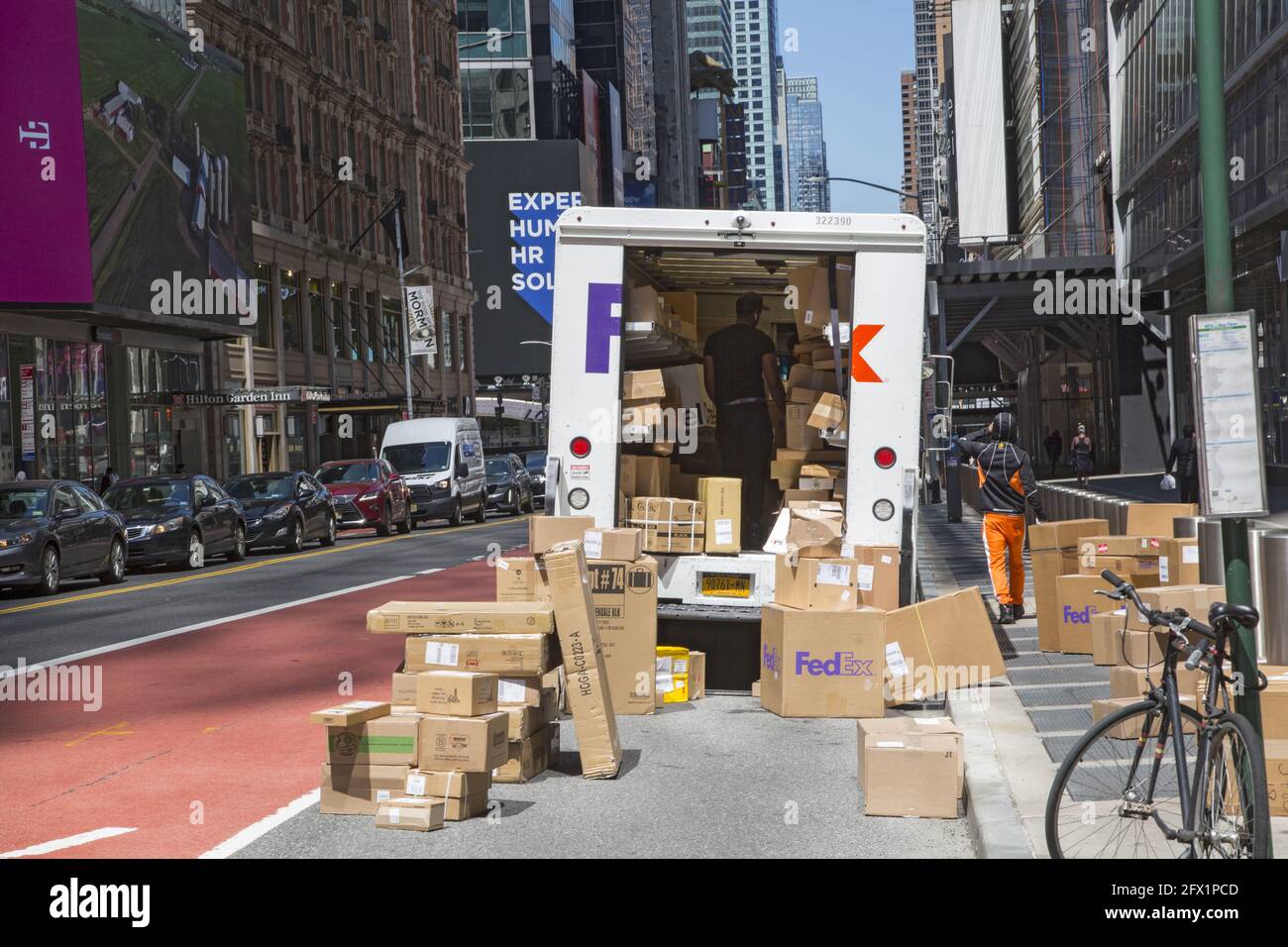 FedEx deliveryman come gli altri principali servizi di consegna è così occupato in questi giorni a causa della chiusura Covid-19 che ha bisogno di utilizzare la strada per risolvere i numerosi pacchetti che ha per la consegna, qui nel centro di Manhattan, New York. Foto Stock