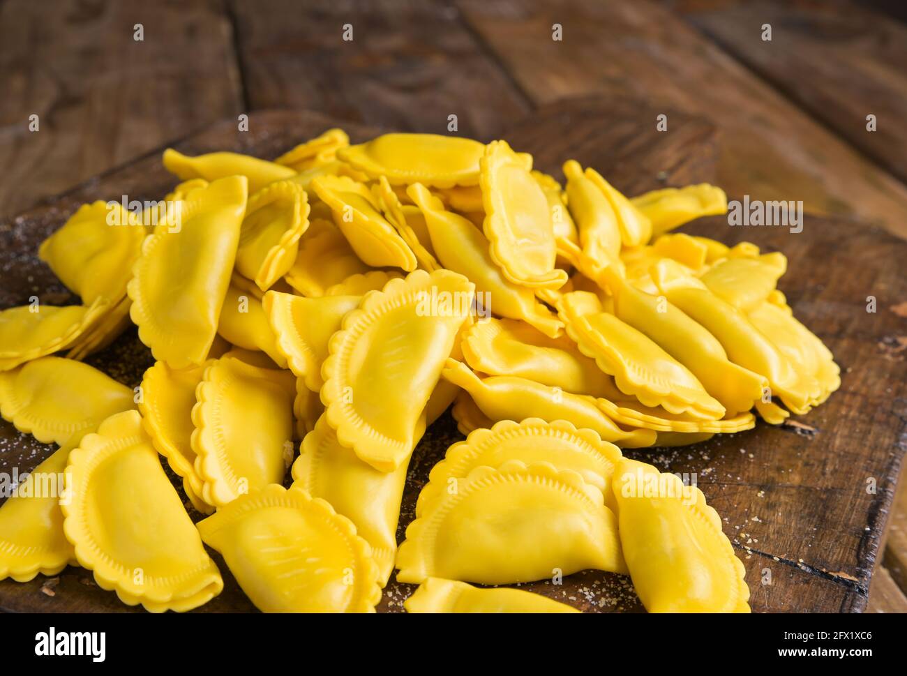 Ravioli piccoli con formaggio o carne da cuocere in brodo, piatto tradizionale per celebrazioni in italia, regione Emilia Romagna. Pasta fresca fatta in casa con ripieno su un tavolo di legno. In avvicinamento dall'alto. Foto Stock