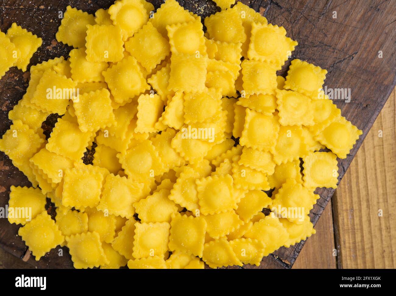 Ravioli piccoli con formaggio o carne da cuocere in brodo, piatto tradizionale per celebrazioni in italia, regione Emilia Romagna. Pasta fresca fatta in casa con ripieno su un tavolo di legno. In avvicinamento dall'alto. Foto Stock
