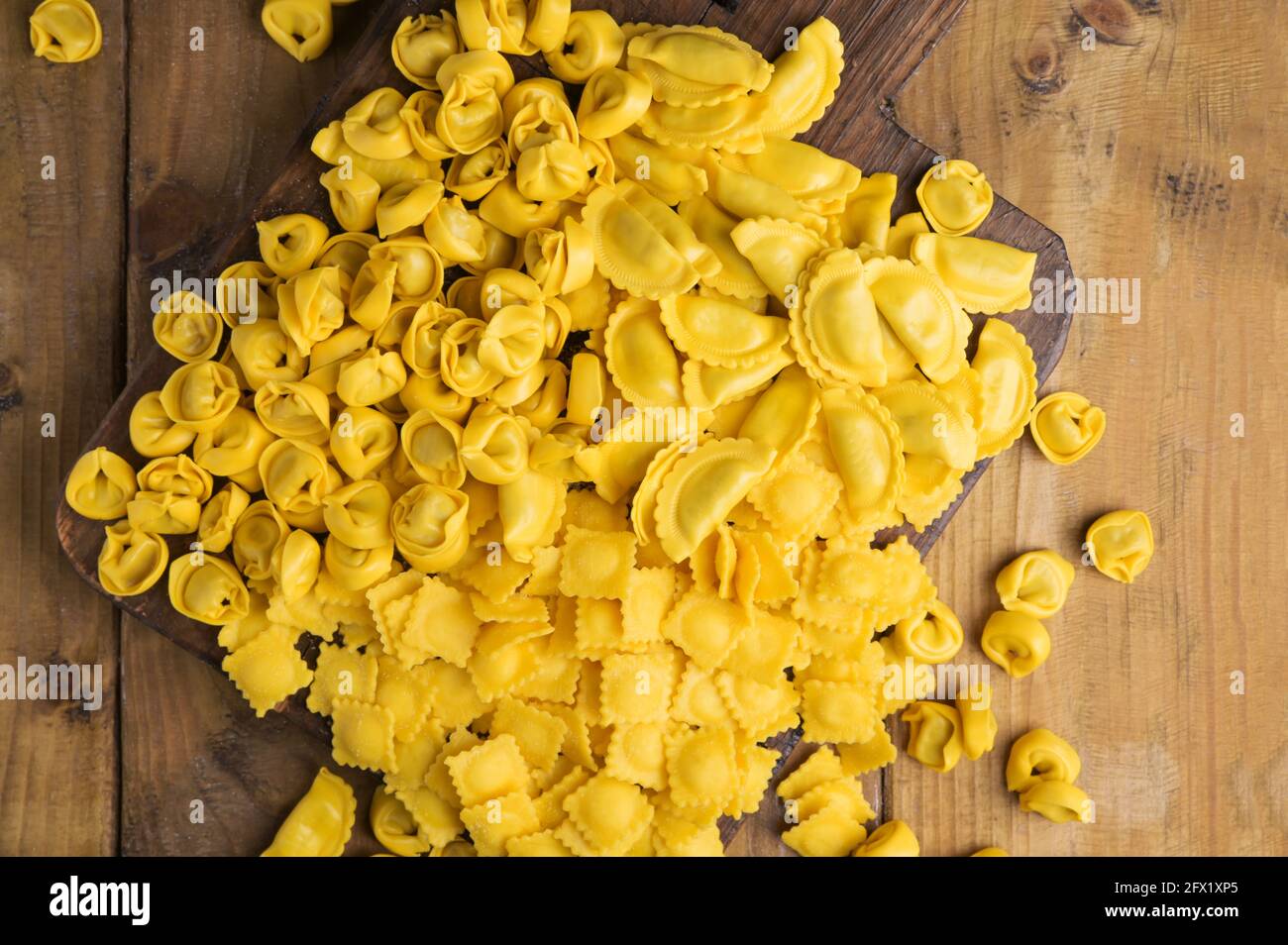 Ravioli piccoli con formaggio o carne da cuocere in brodo, piatto tradizionale per celebrazioni in italia, regione Emilia Romagna. Pasta fresca fatta in casa con ripieno su un tavolo di legno. In avvicinamento dall'alto. Foto Stock