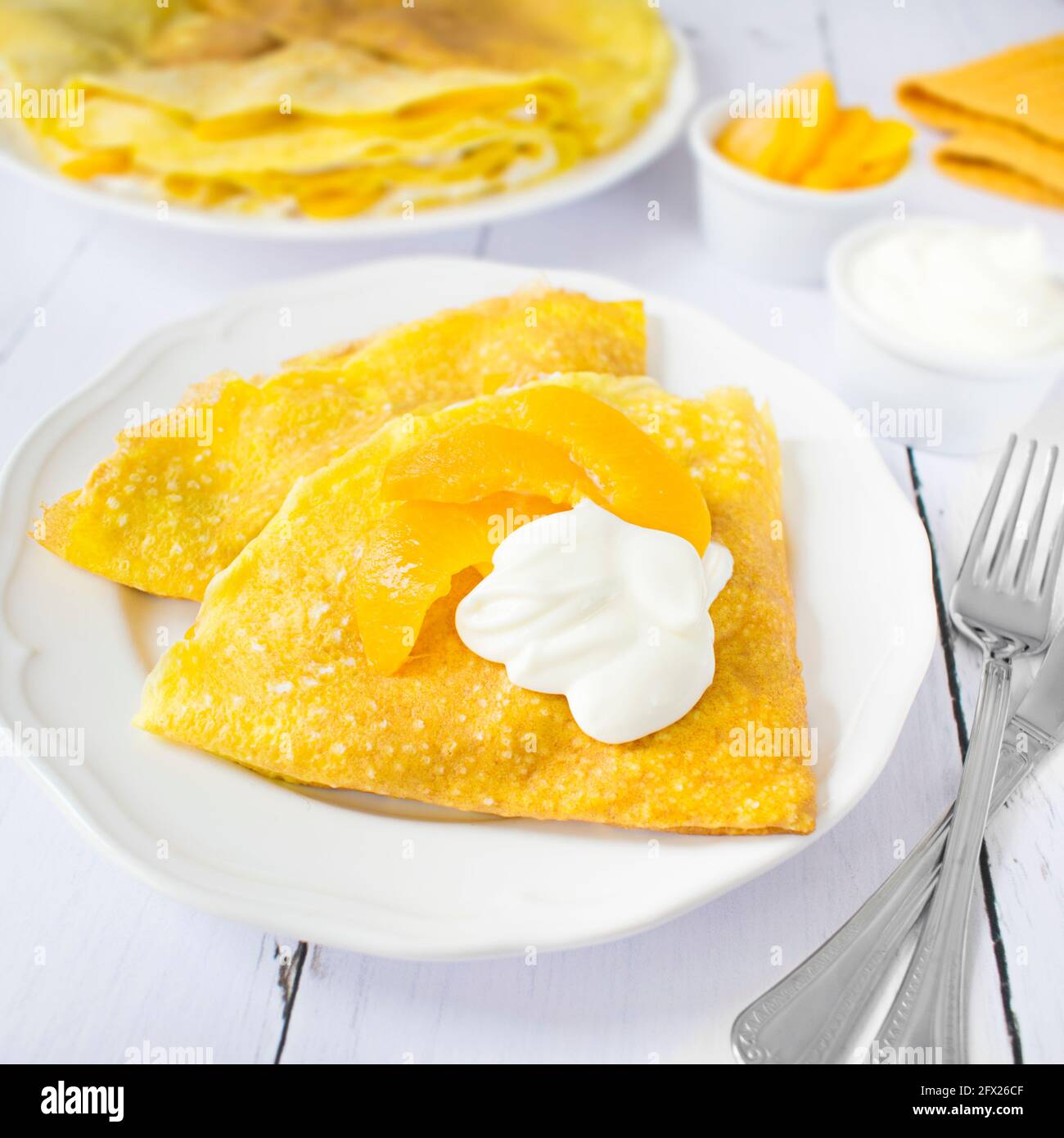 Frittelle dolci con formaggio di cottage e pesche, condite con crema dolce. Foto Stock