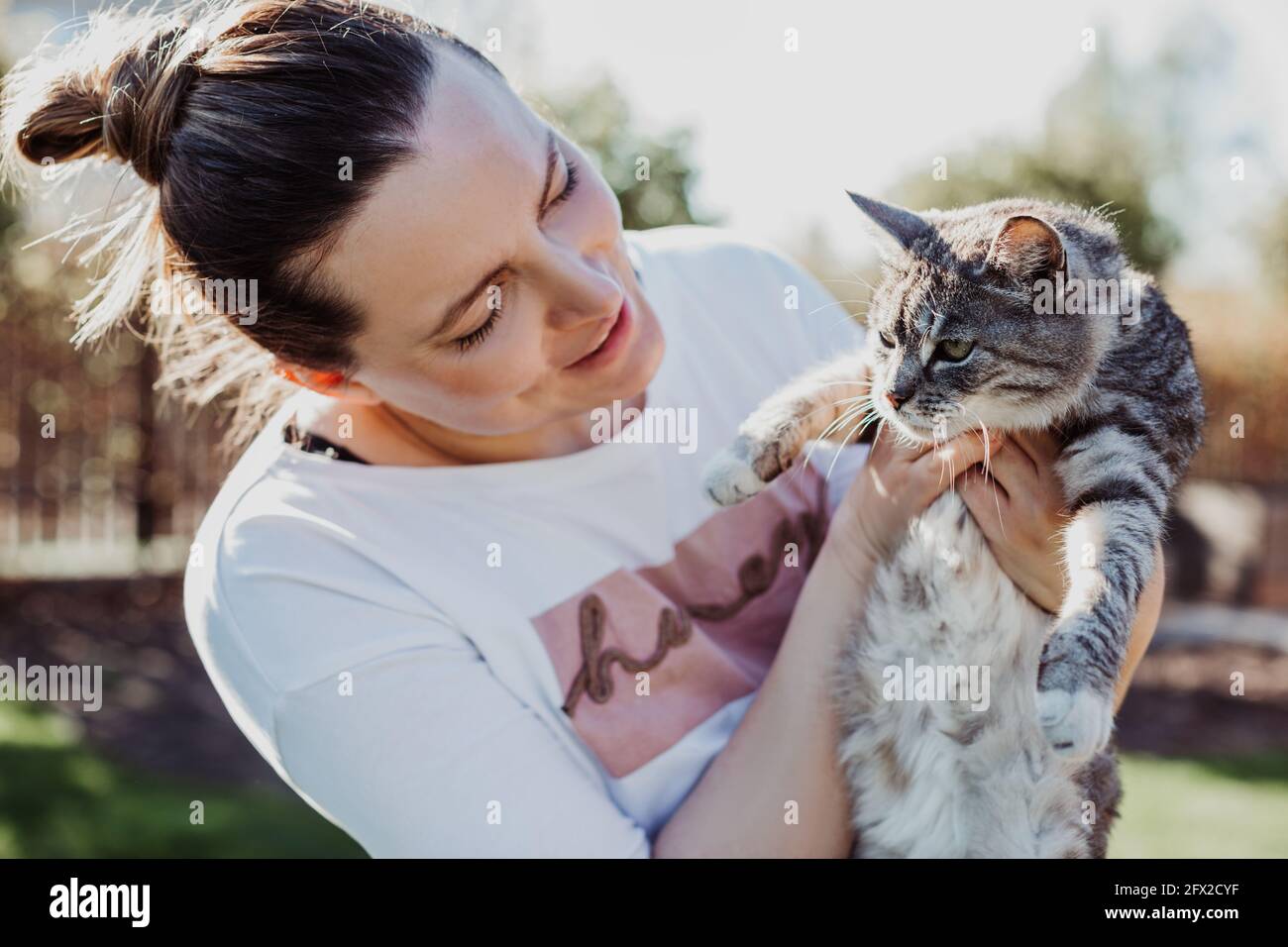 donna ammira il suo animale domestico, lo tiene in braccio il giorno di sole Foto Stock