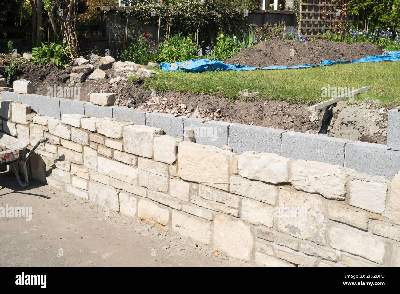 Un muro di ritegno giardino di fronte pietra in costruzione Foto Stock