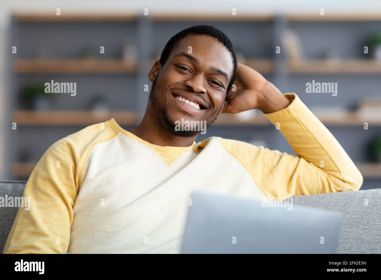 Primo piano di un ragazzo nero con un computer portatile che sorride alla fotocamera Foto Stock