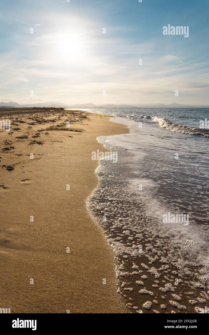 Spiaggia di sabbia dorata e mare blu. Il mare è calmo con piccole onde. Il cielo è blu. Paesaggio non affollato. Foto Stock