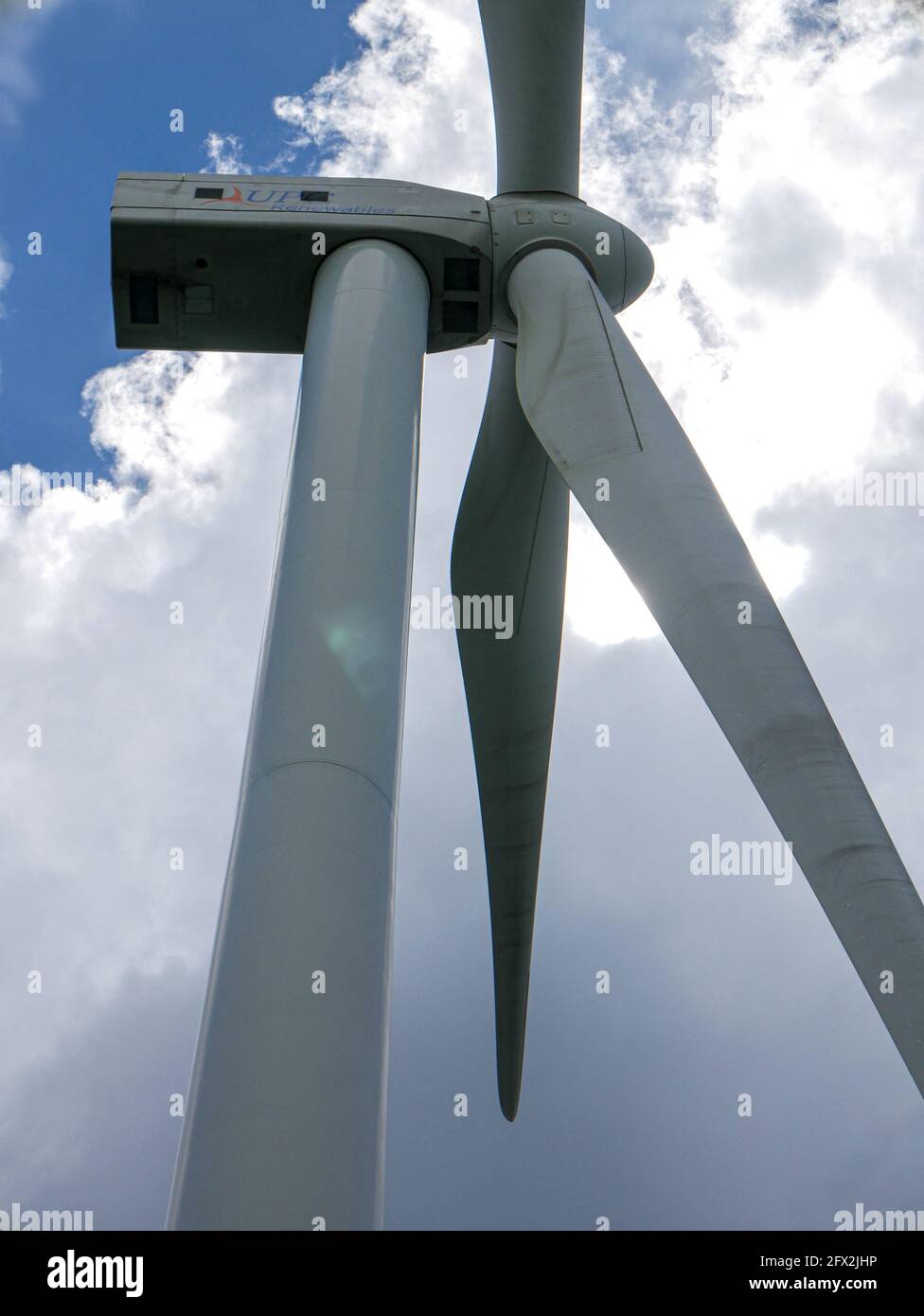 Turbine eoliche sul verde terreno collinare con il cielo blu luminoso. Foto Stock